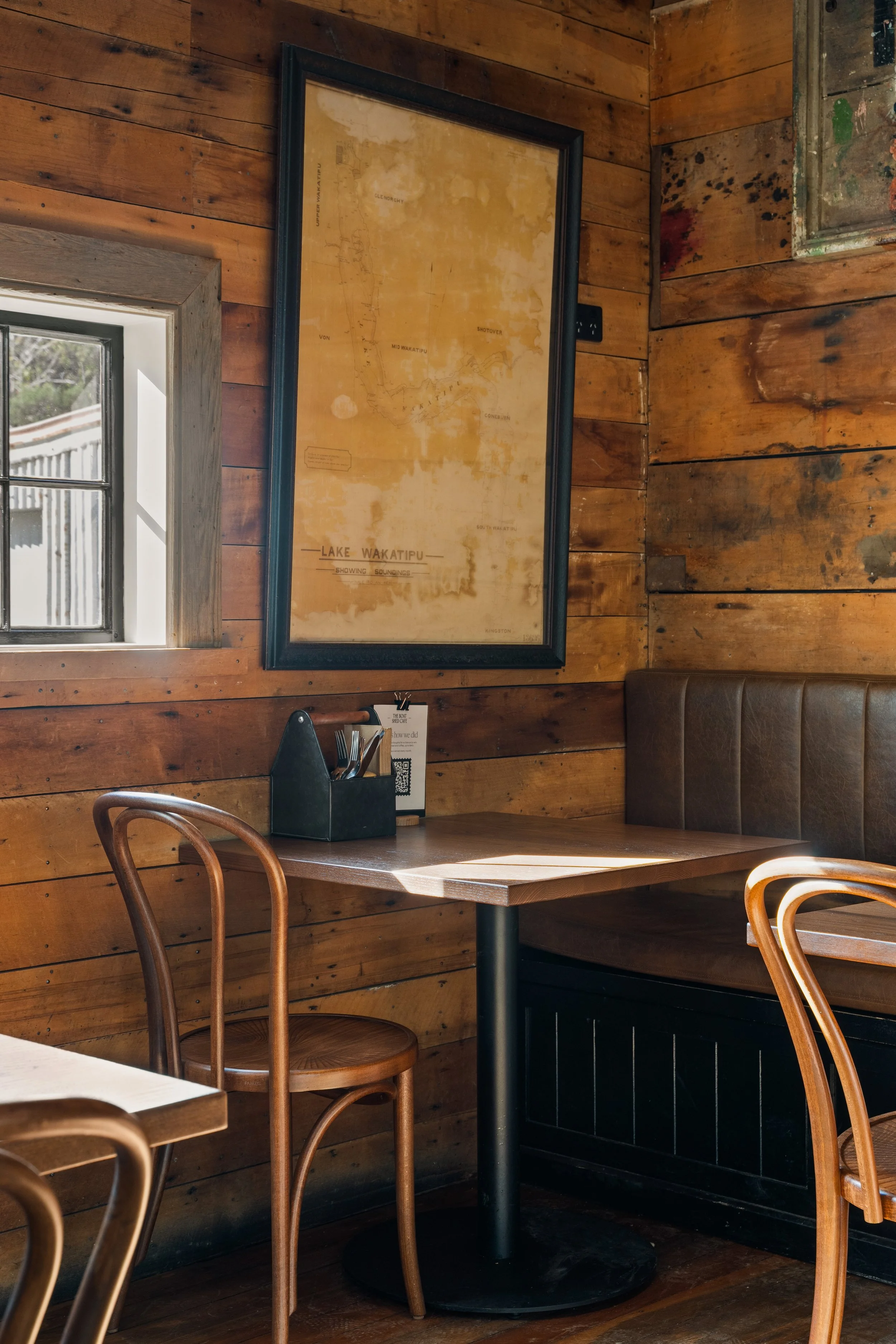 Cosy corner table with reclaimed timber walls and framed map, heritage cafe renovation