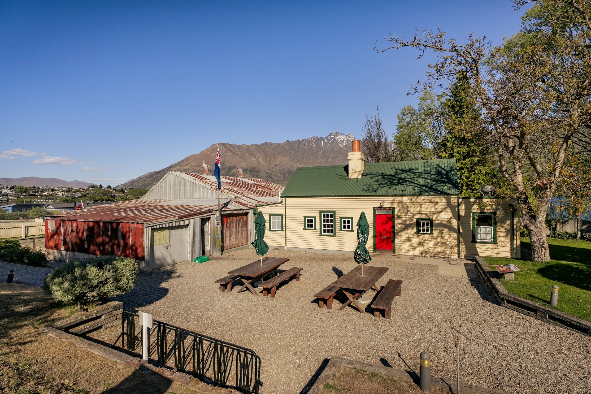 Heritage Boat Shed Cafe and courtyard with picnic tables and mountain backdrop, Frankton Marina