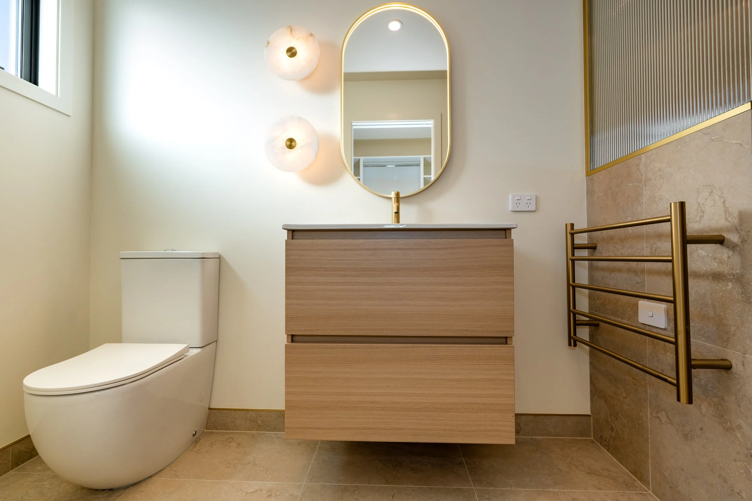 Contemporary master ensuite featuring a custom floating vanity, premium brass tapware, large-format tiles and modern bathroom design in a Queenstown home by Adept Carpentry.