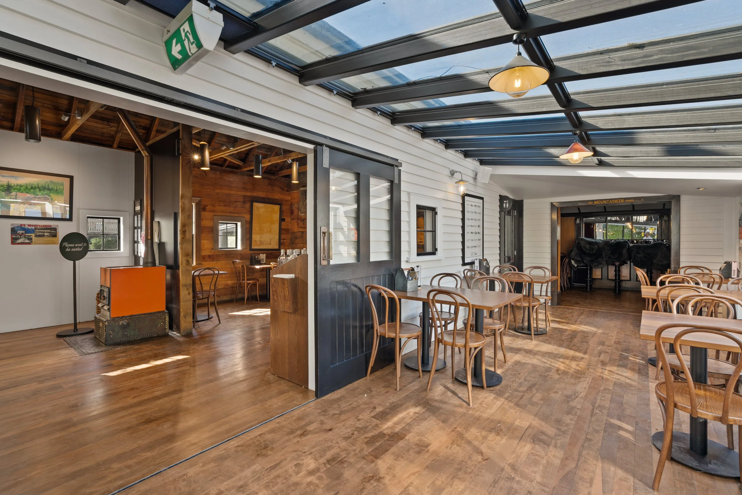 Timber floor dining area with glazed doors and glass roof, Queenstown cafe renovation