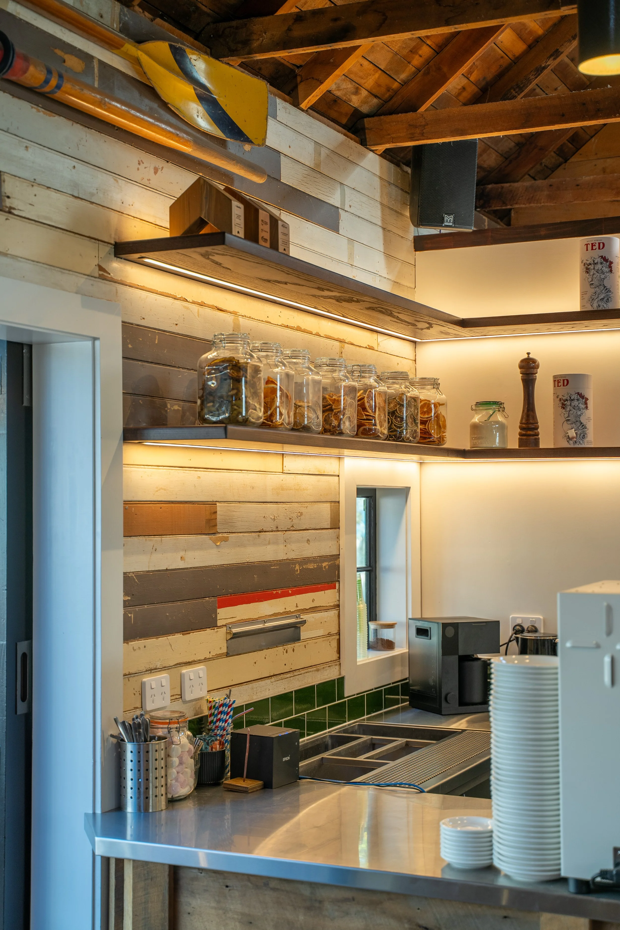 Custom timber shelving with feature lighting and green tiled bench, cafe fit-out Queenstown