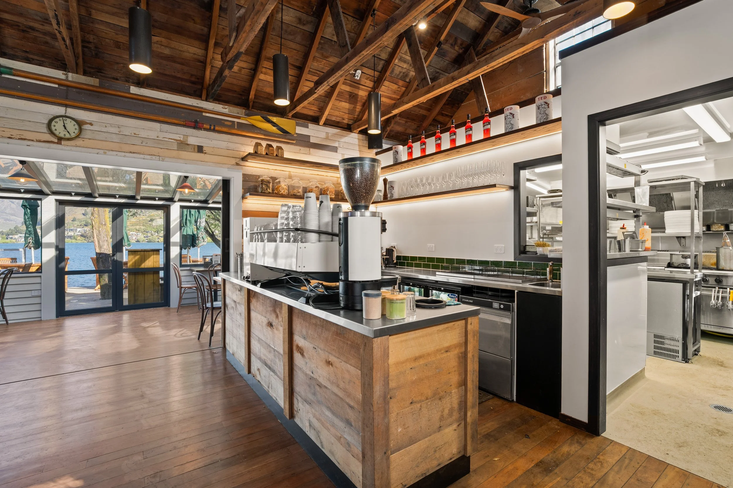 Custom timber coffee bar with espresso grinder under exposed roof trusses, Queenstown cafe