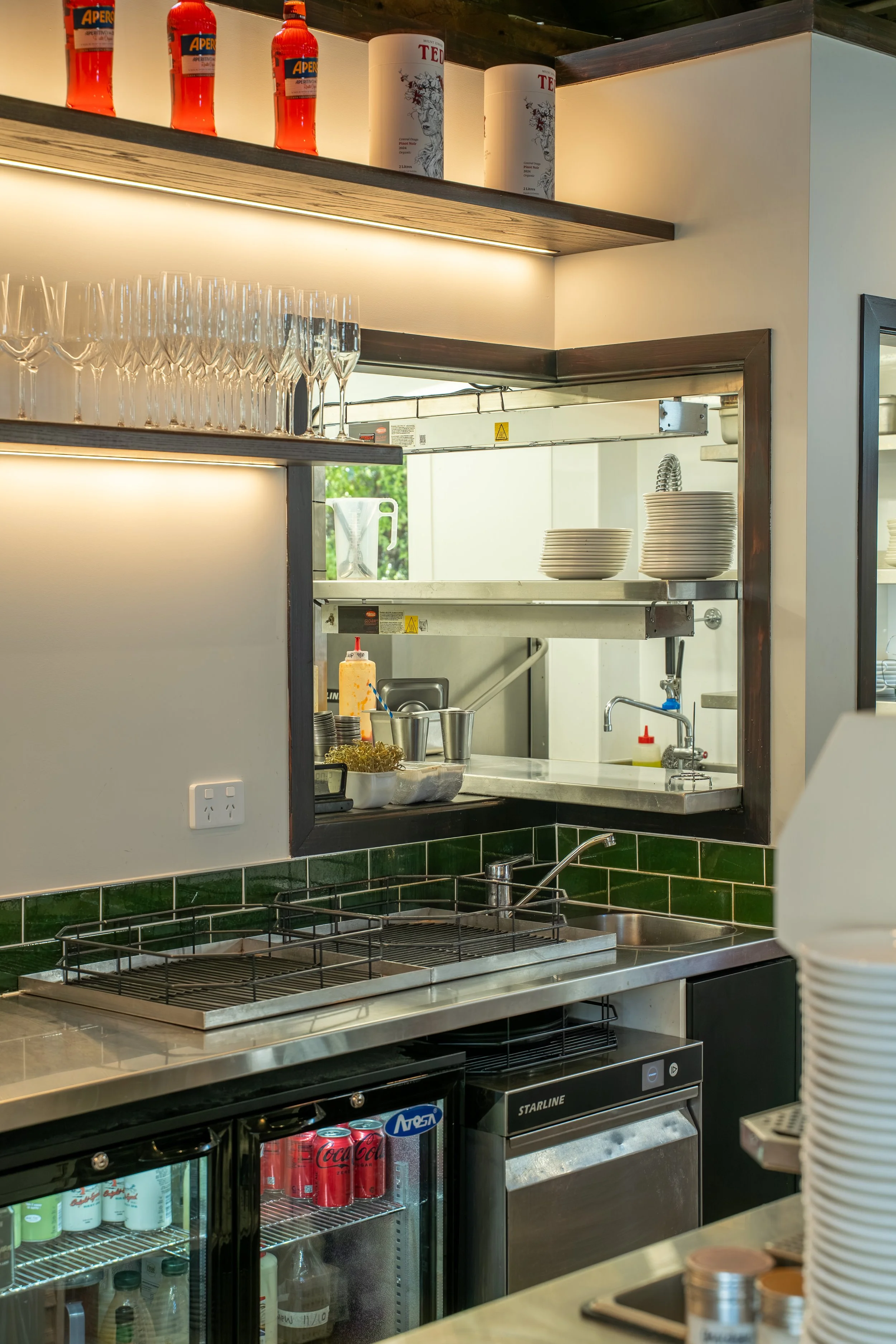 Commercial kitchen pass-through window with green tiled splashback, cafe fit-out Queenstown