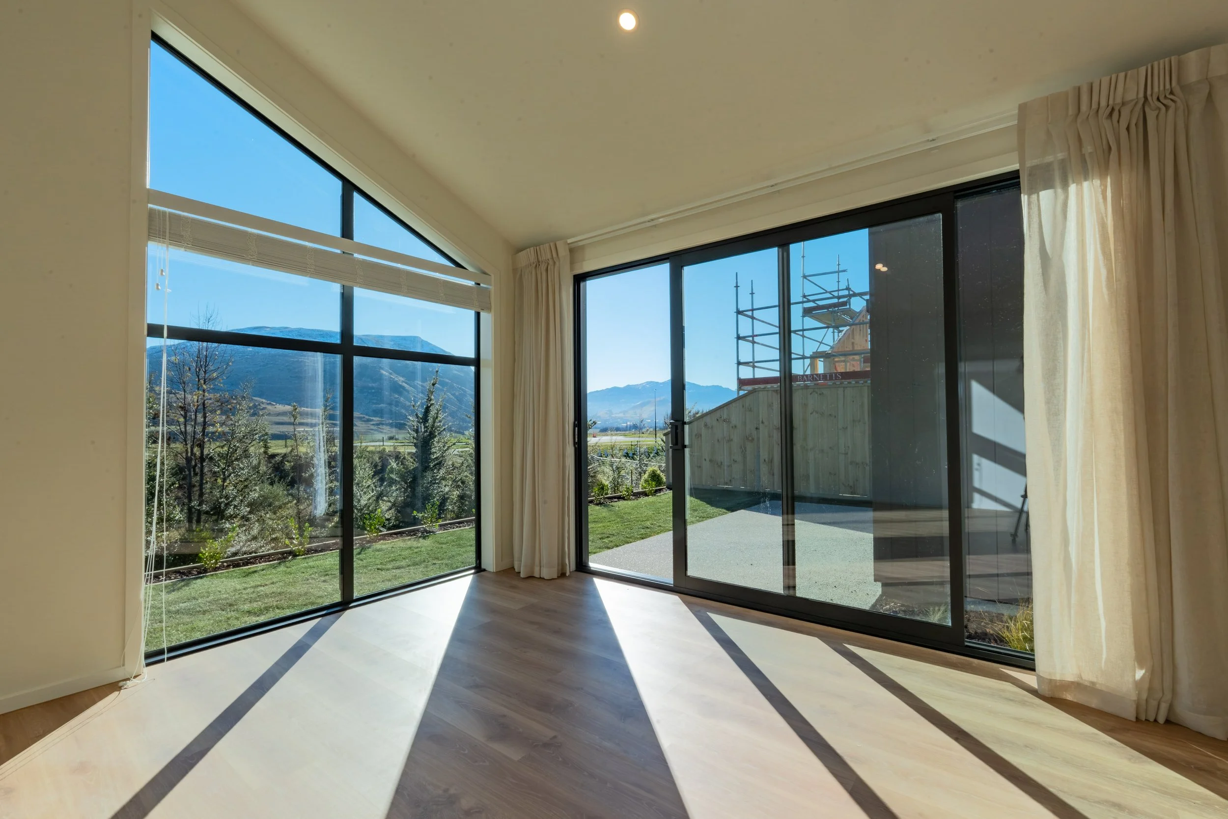 Bright open-plan living and kitchen featuring Scandinavian-inspired styling, custom cabinetry, premium finishes and contemporary residential construction in Queenstown.