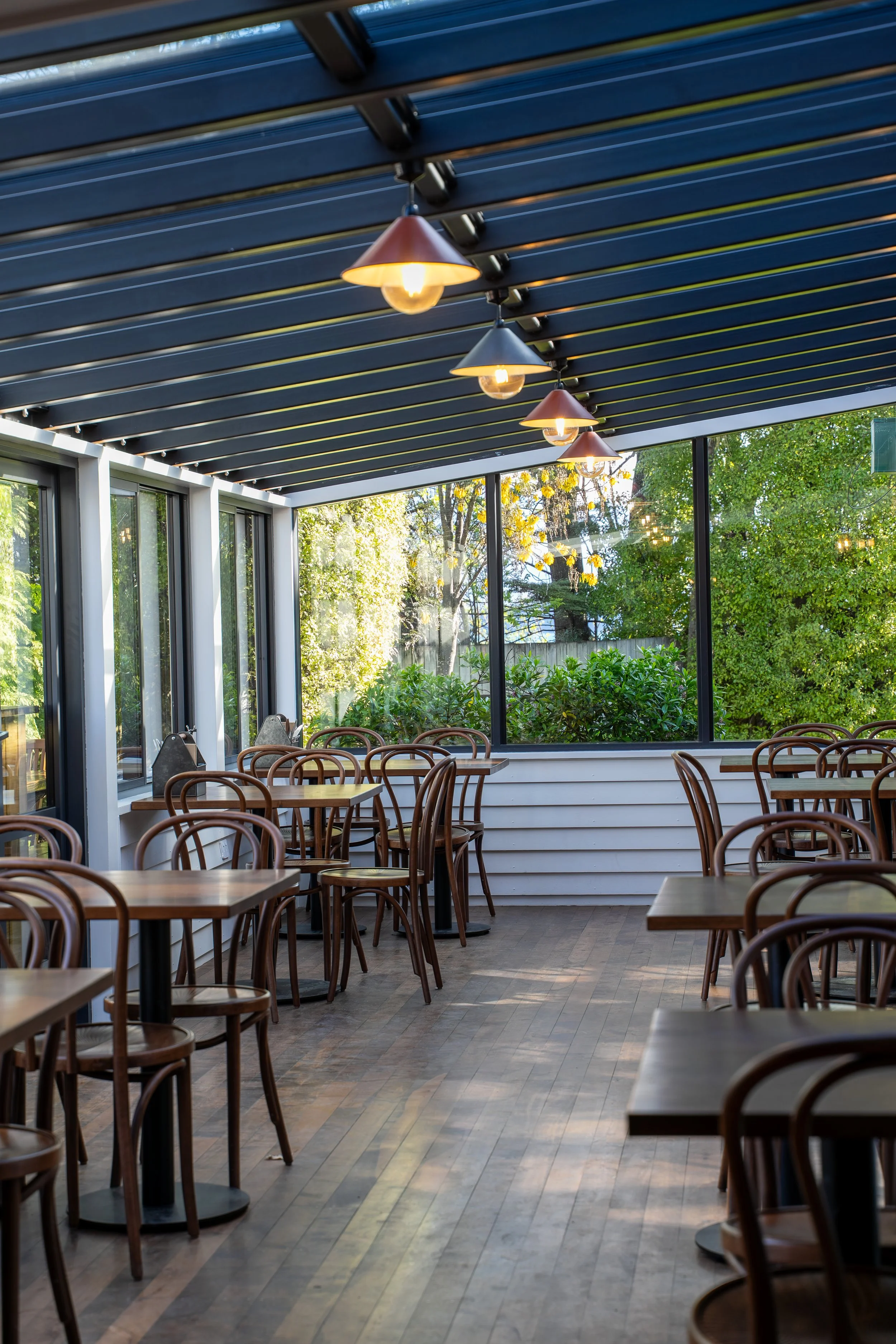 Glasshouse dining area with pendant lights, Boat Shed Cafe renovation Queenstown