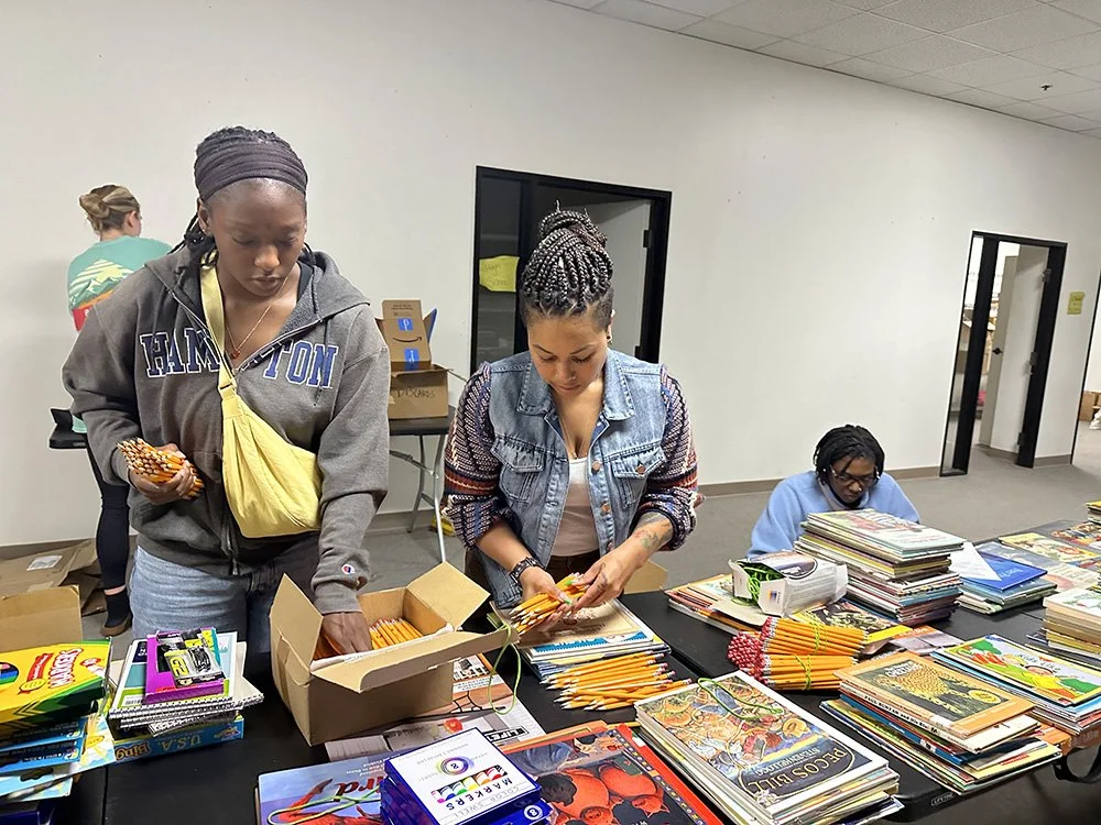 A diverse group of four volunteers sorting schools supplies at a sort and pack session