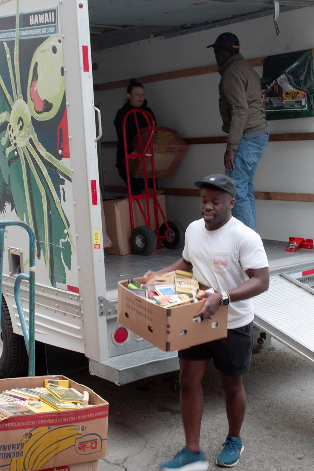 Three volunteers unloading books from a truck