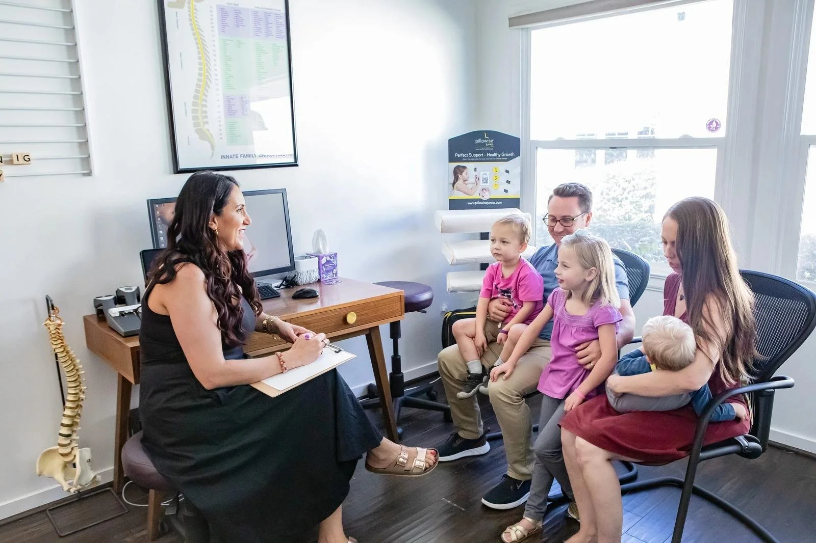 Dr. Adana Vargas of Innate Family Chiropractic Pasadena CA in consultation with a family — multiple children present.