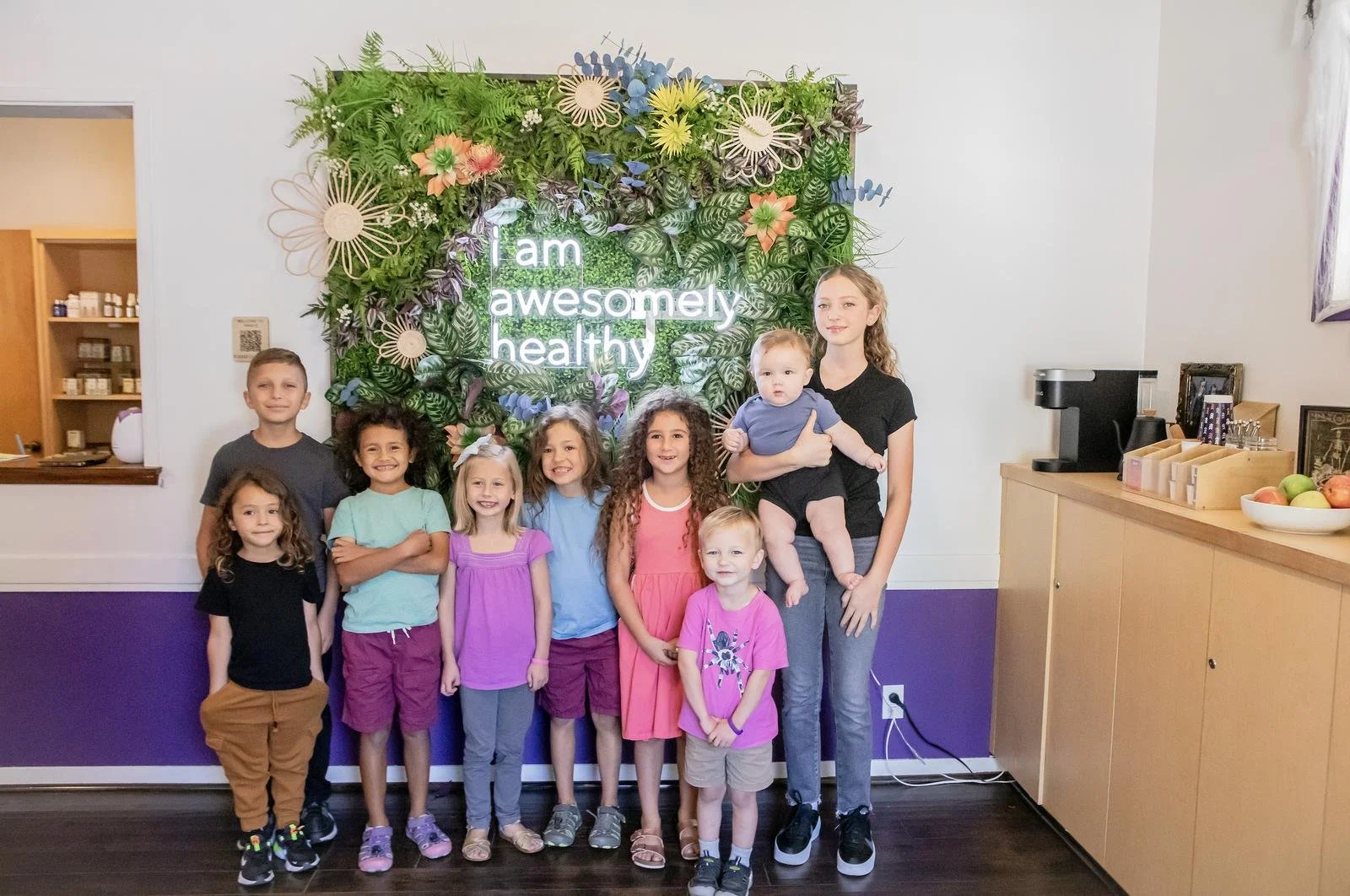 Children gathered at the 'I am awesomely healthy' flower wall inside Innate Family Chiropractic Pasadena CA.