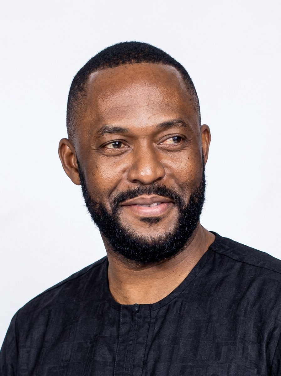 A portrait of a man with a beard and short hair, wearing a black shirt, looking slightly to the right with a neutral background.