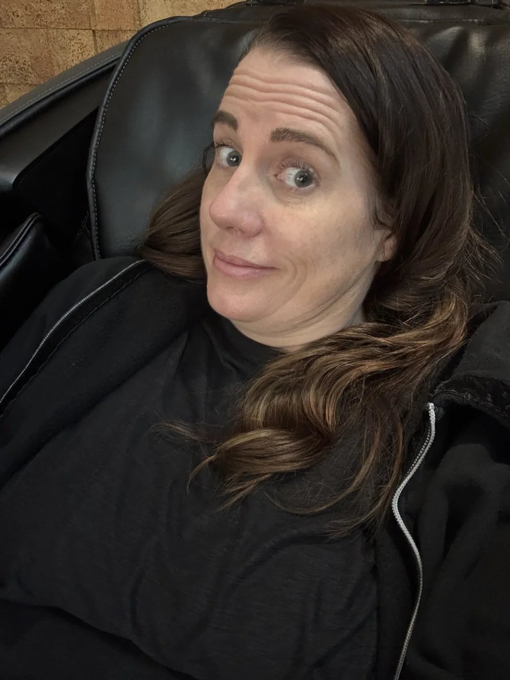 Traveler relaxing in an XWELL zero-gravity massage chair during a JFK Airport layover before flying to Milan.