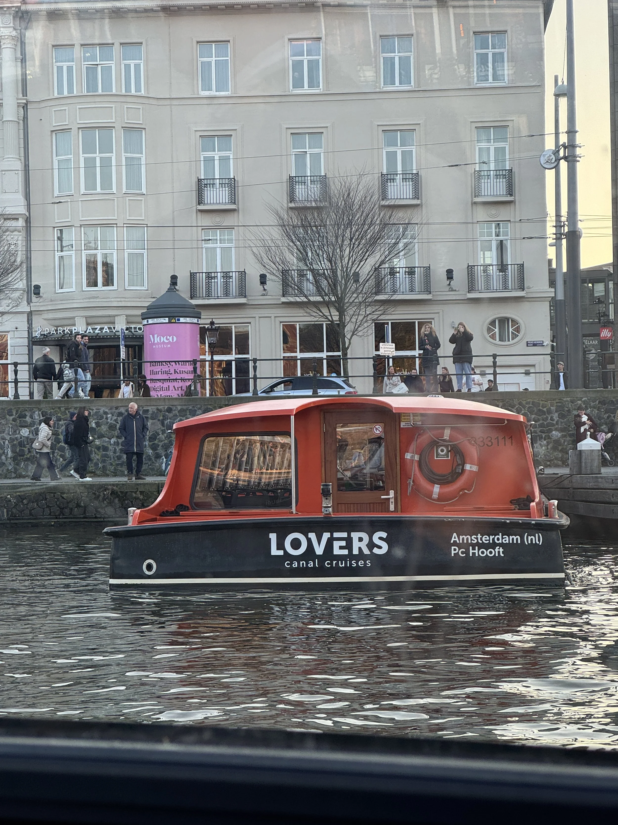 Lovers Canal Cruise boat traveling along an Amsterdam canal with historic buildings in the background