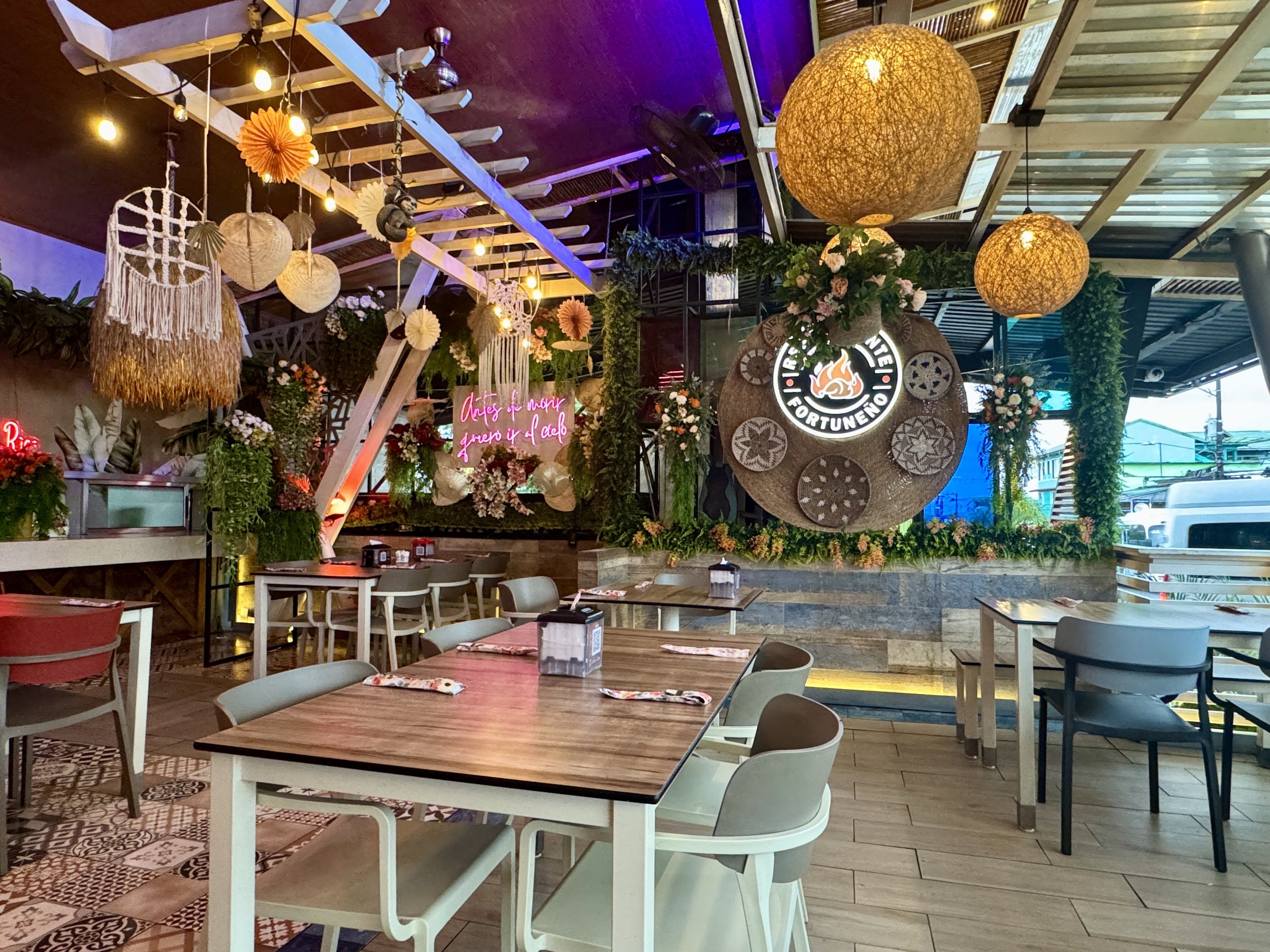 Stylish dining area with decorative hanging lamps, plants, and modern seating inside Restaurante Fortuñeño.