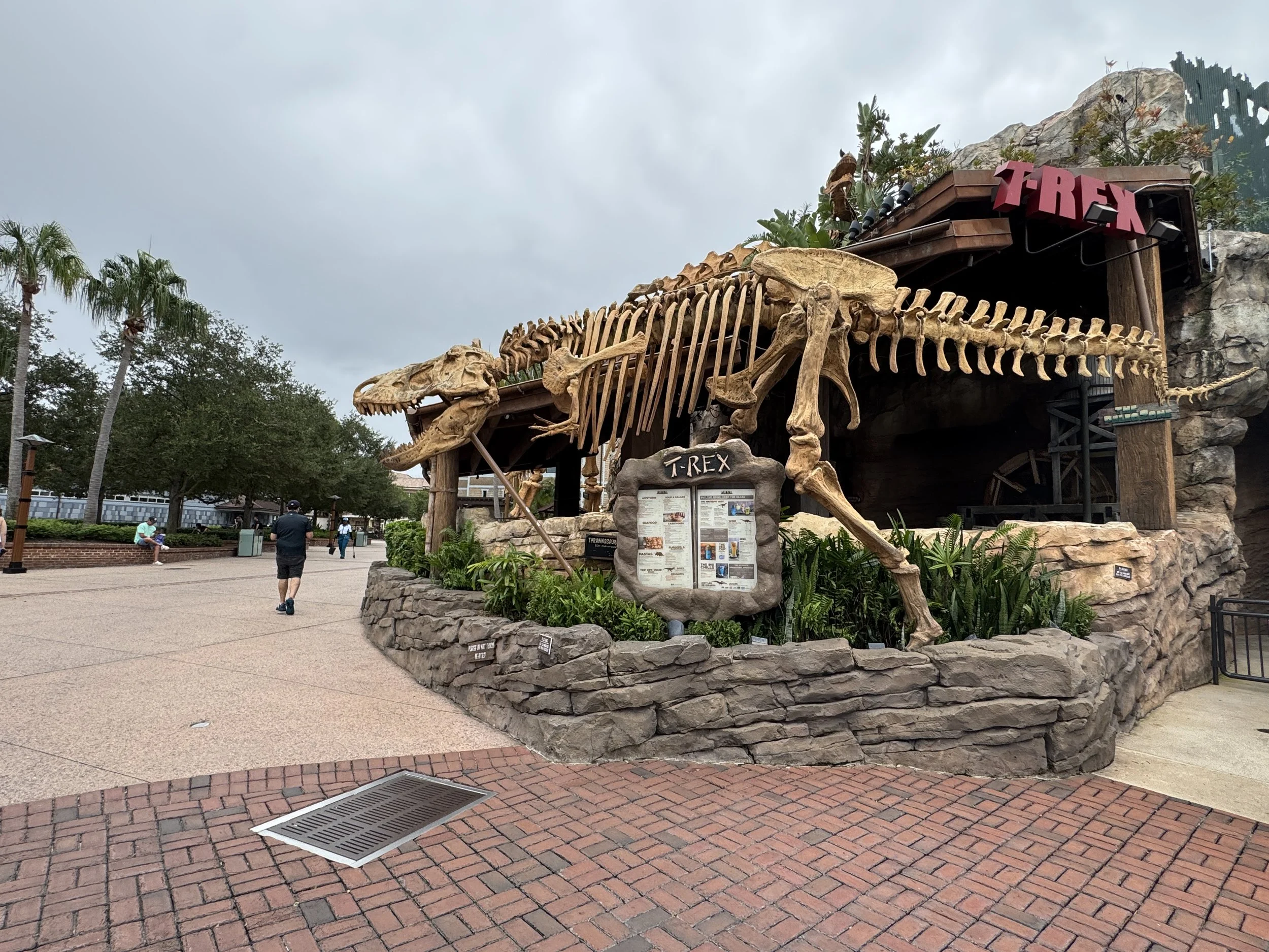 Entrance to T-Rex Cafe at Disney Springs featuring a giant dinosaur skeleton sculpture.