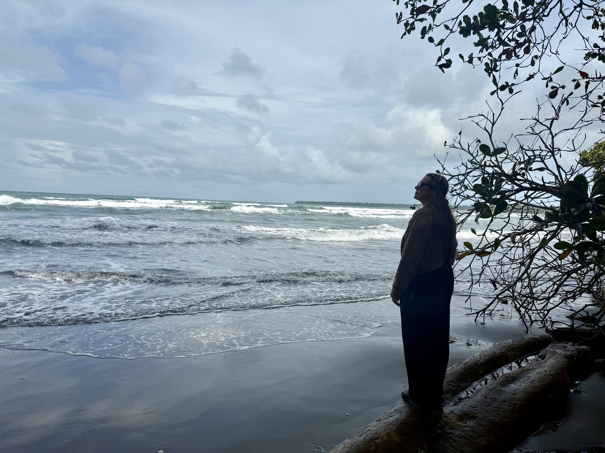 Silhouette of a person standing on the beach at Playa Negra looking out at the ocean.