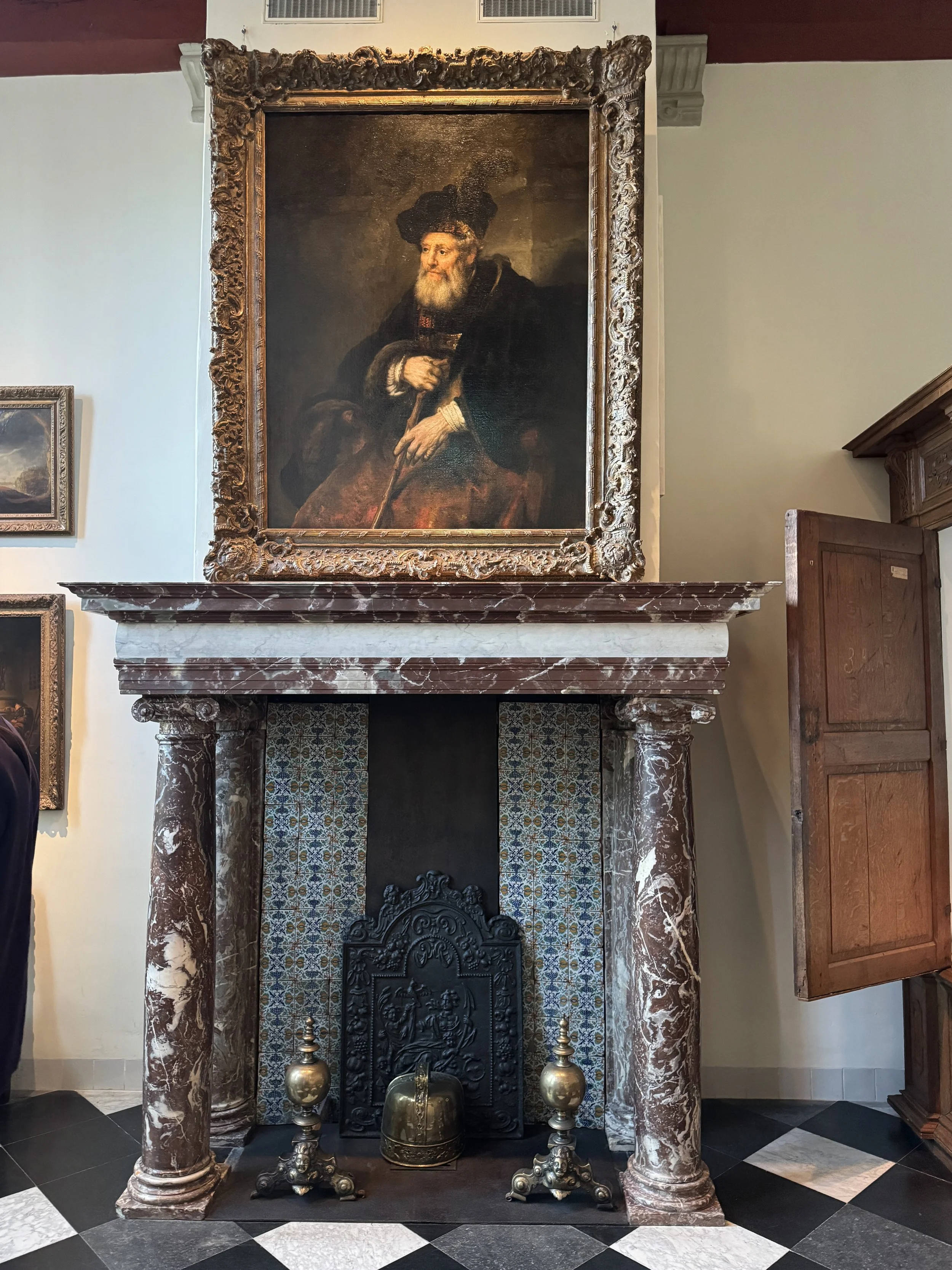 Historic room with ornate fireplace and portrait painting inside Rembrandt House Museum Amsterdam
