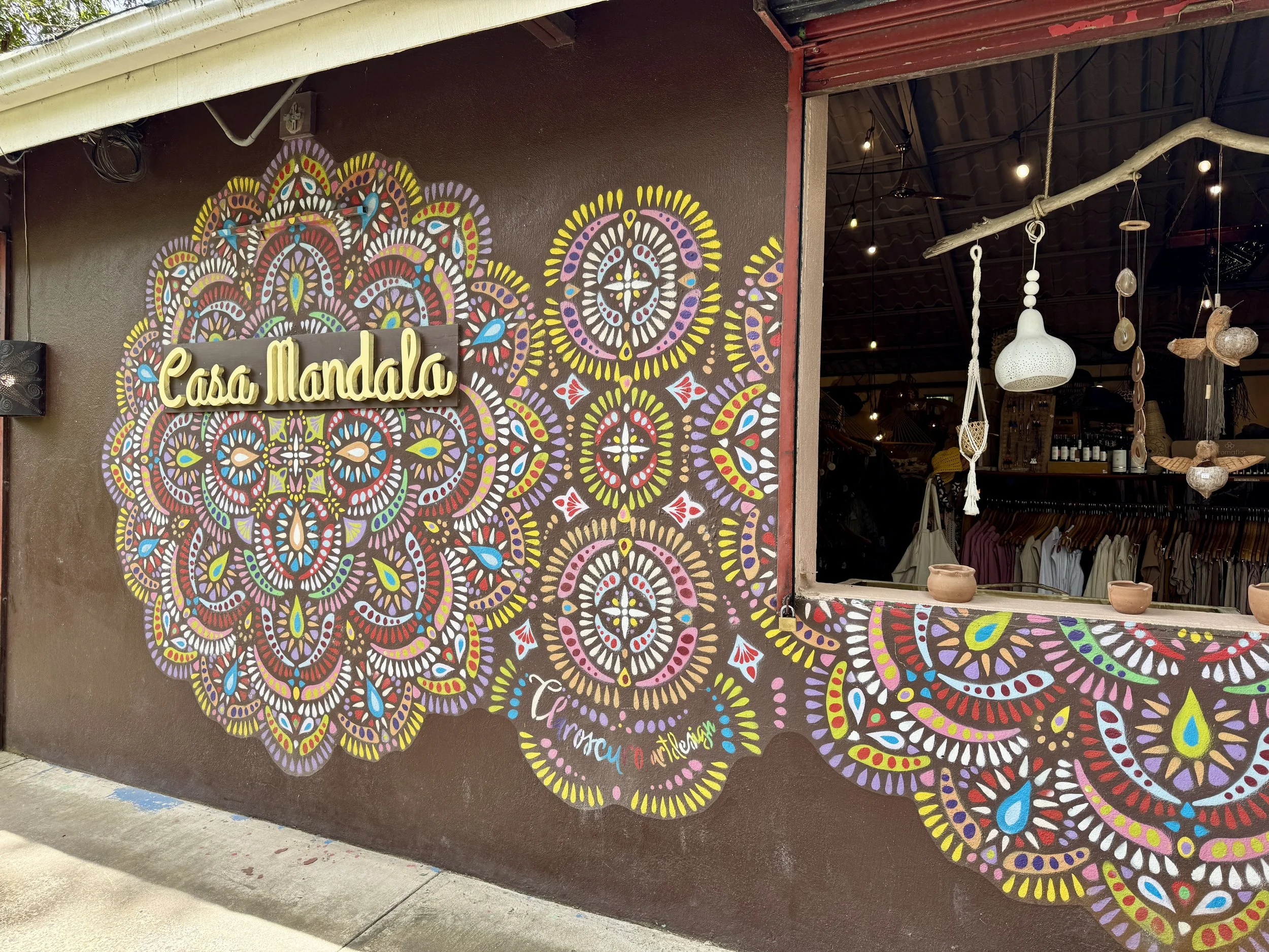 Exterior mural and storefront window of Casa Mandala featuring vibrant circular artwork.