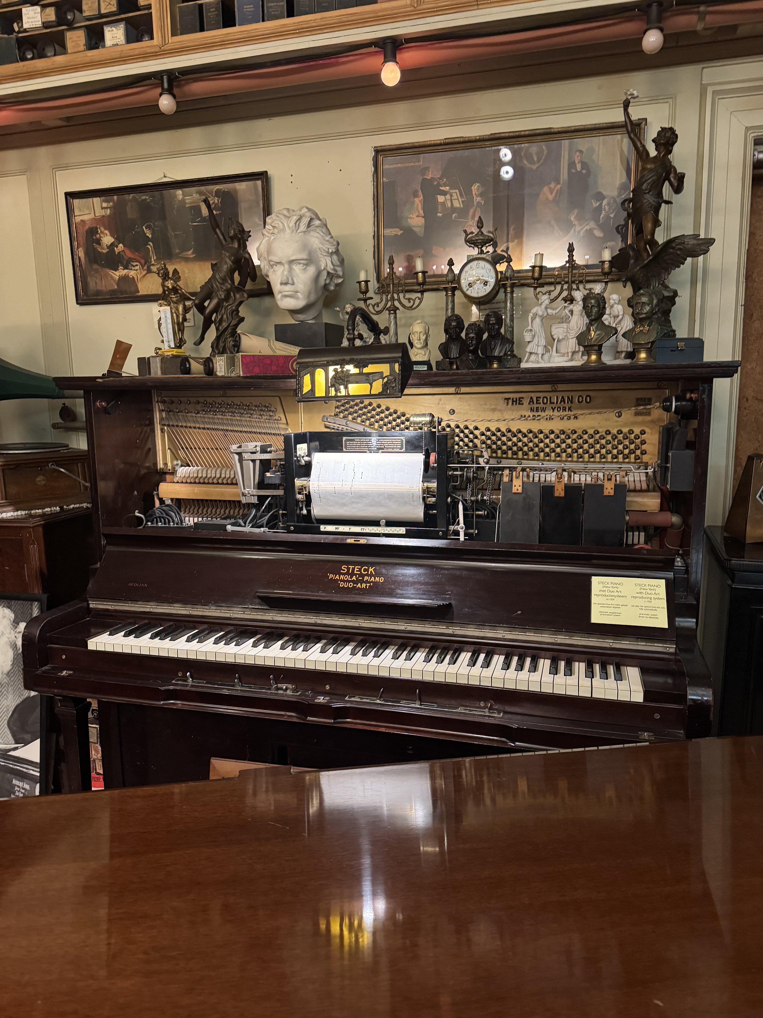 Vintage upright piano surrounded by historic instruments and decor at Geelvinck Pianola Museum in Amsterdam