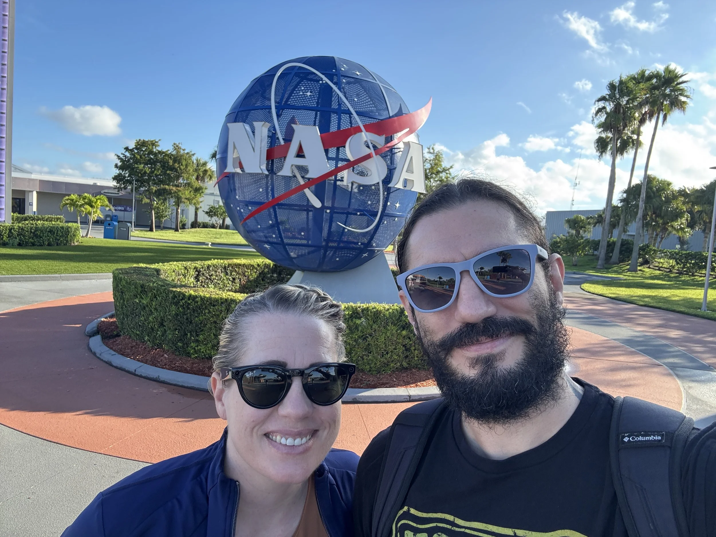 Visitors posing in front of the NASA globe sculpture at Kennedy Space Center Visitor Complex.