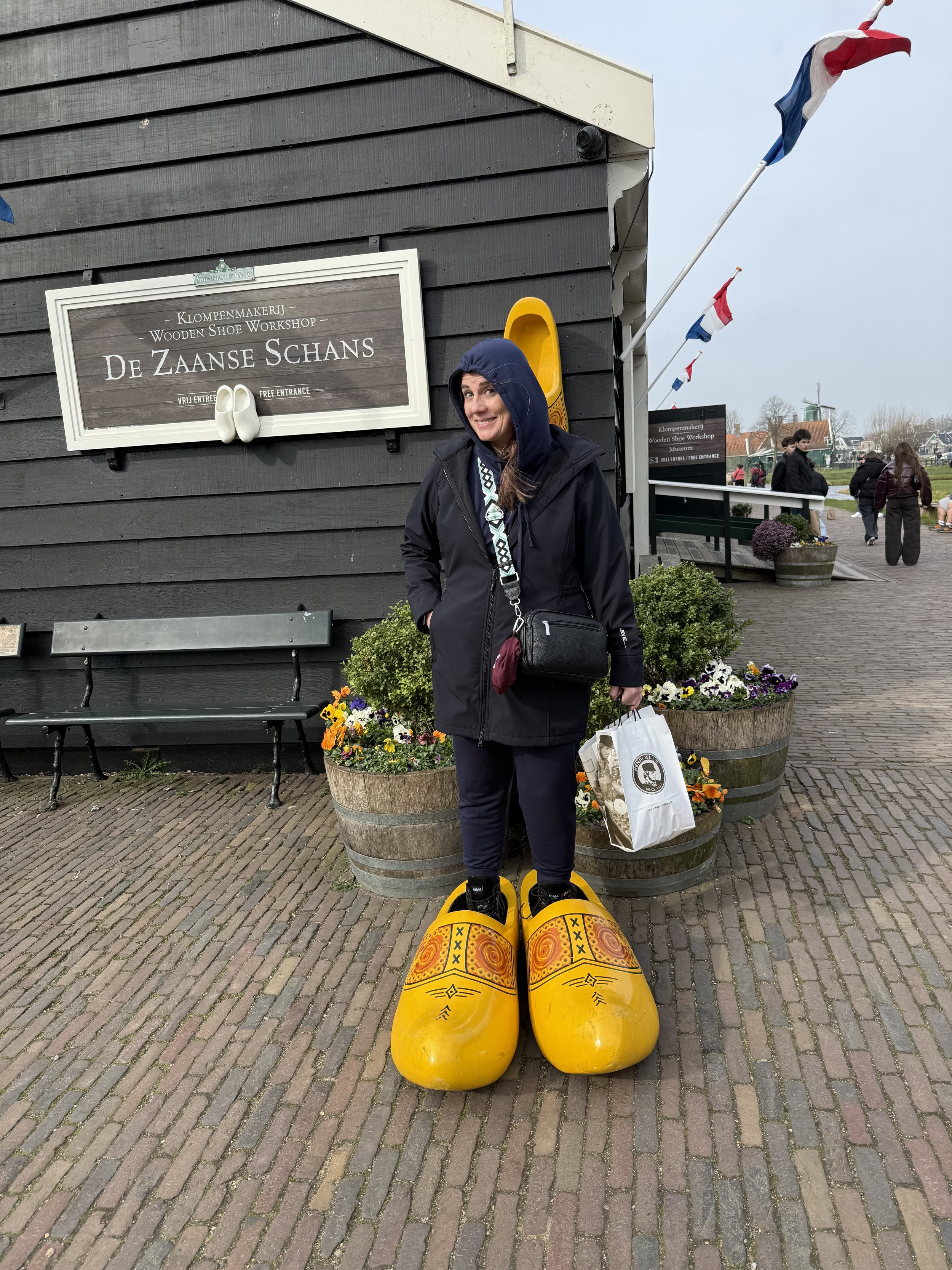 Visitor posing with oversized wooden clogs at Zaanse Schans in the Netherlands