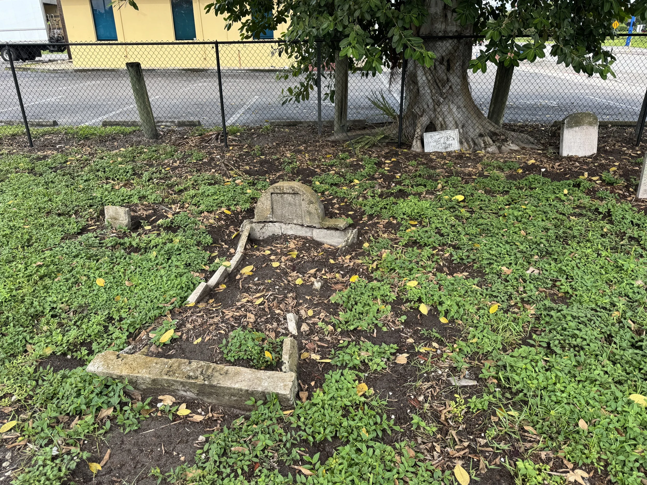 Old tombstone and small gravesite surrounded by grass and trees from a long-forgotten church cemetery in Southwest Florida.