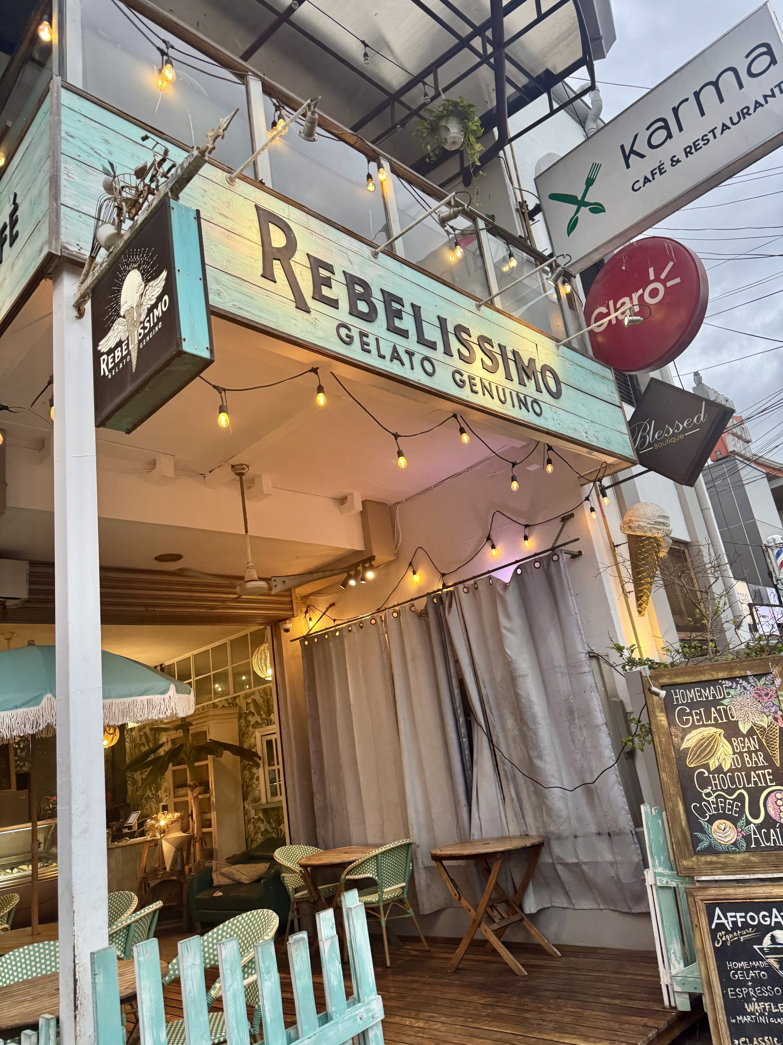 Exterior sign for Rebelissimo Gelato Genuino hanging above a cozy street-front shop.