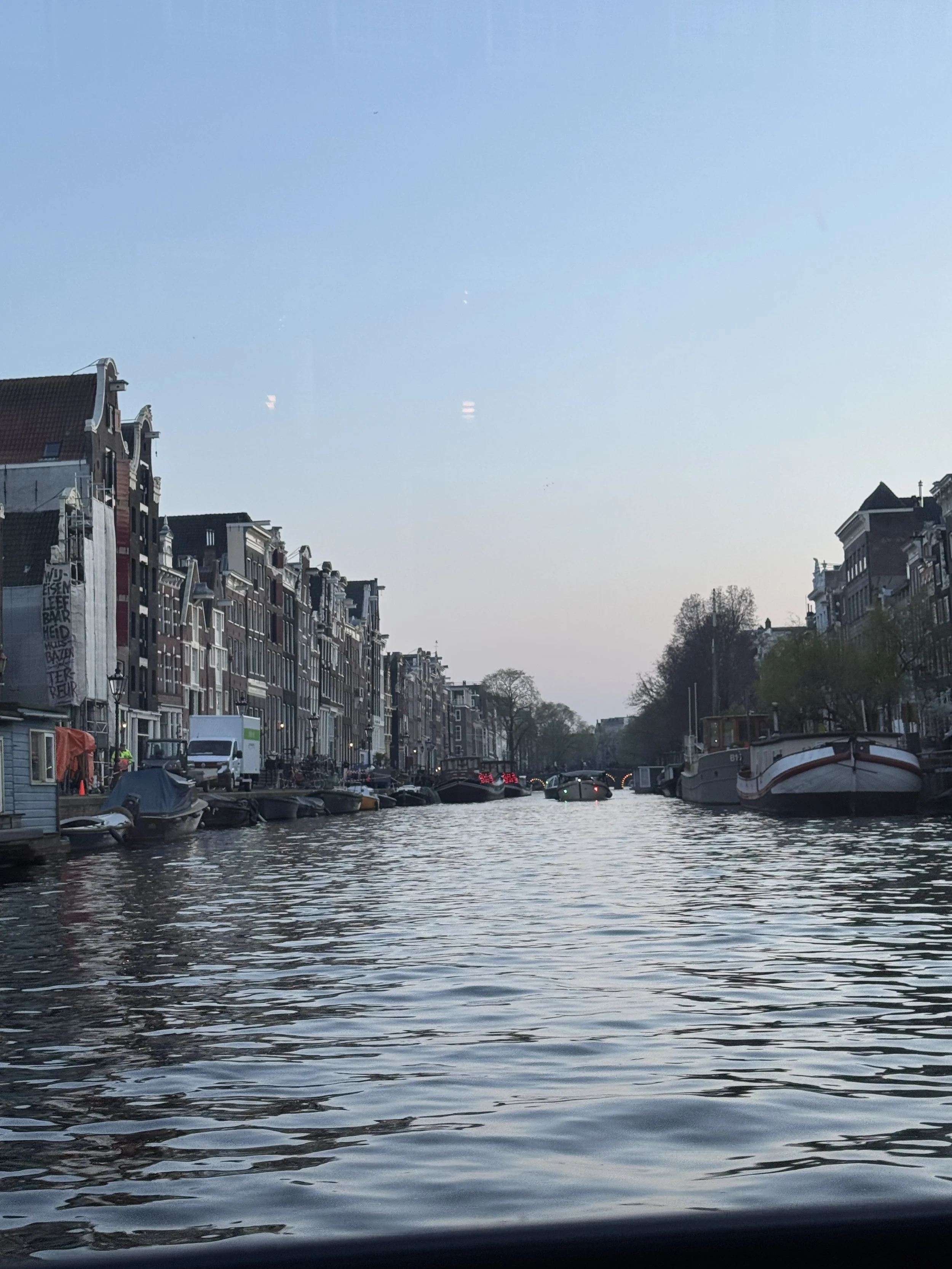 Scenic view down an Amsterdam canal with boats, bridges, and historic buildings