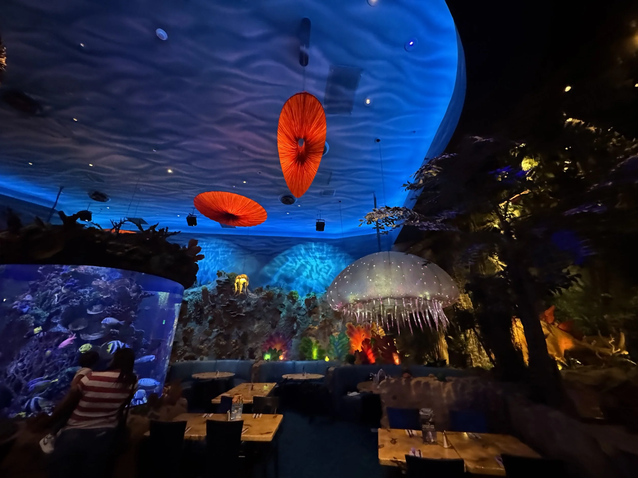 Colorful underwater themed dining room inside T-Rex Cafe with glowing jellyfish lights.