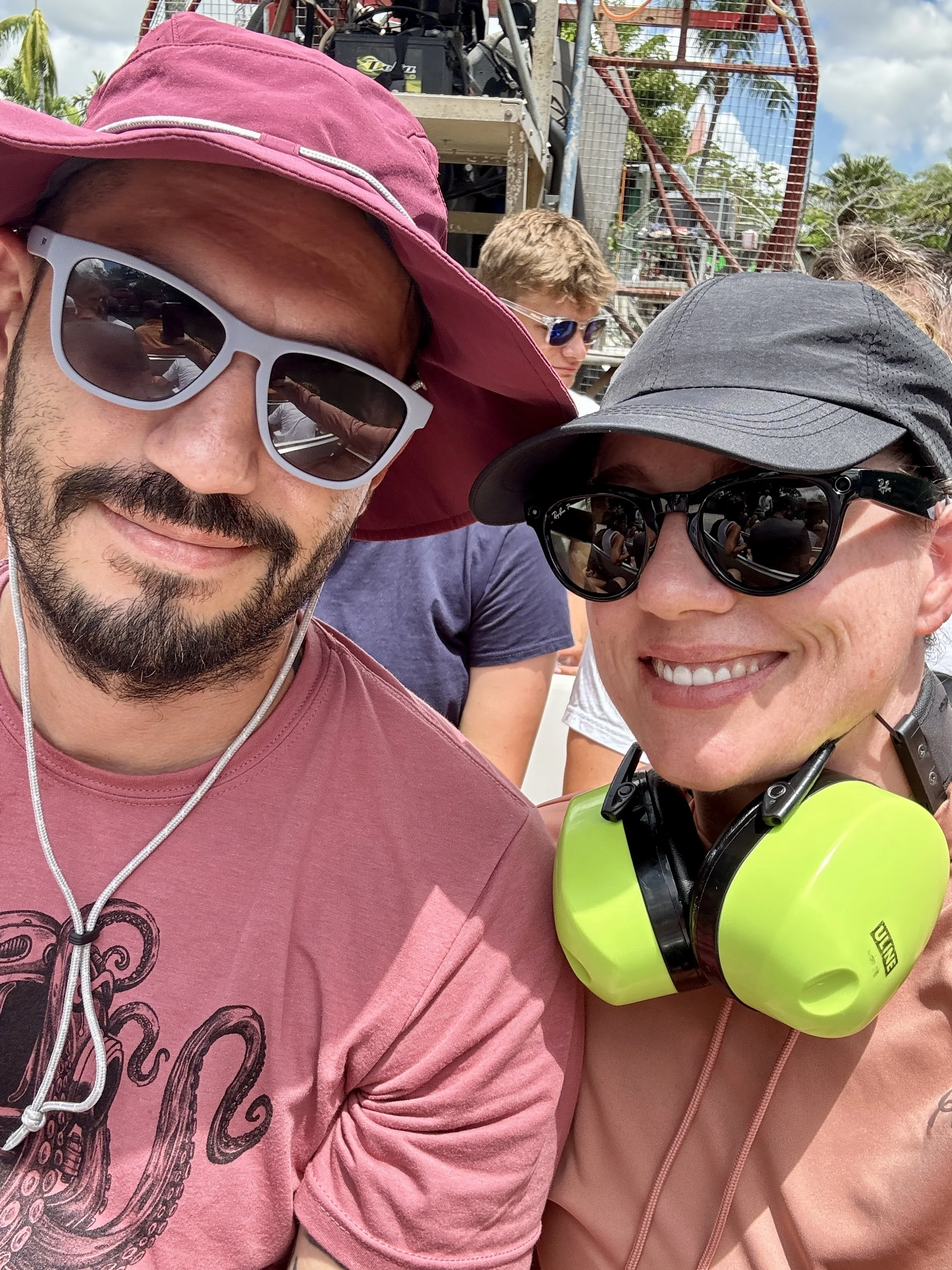 couple wearing sunglasses and bright green ear protection taking a selfie before the airboat ride