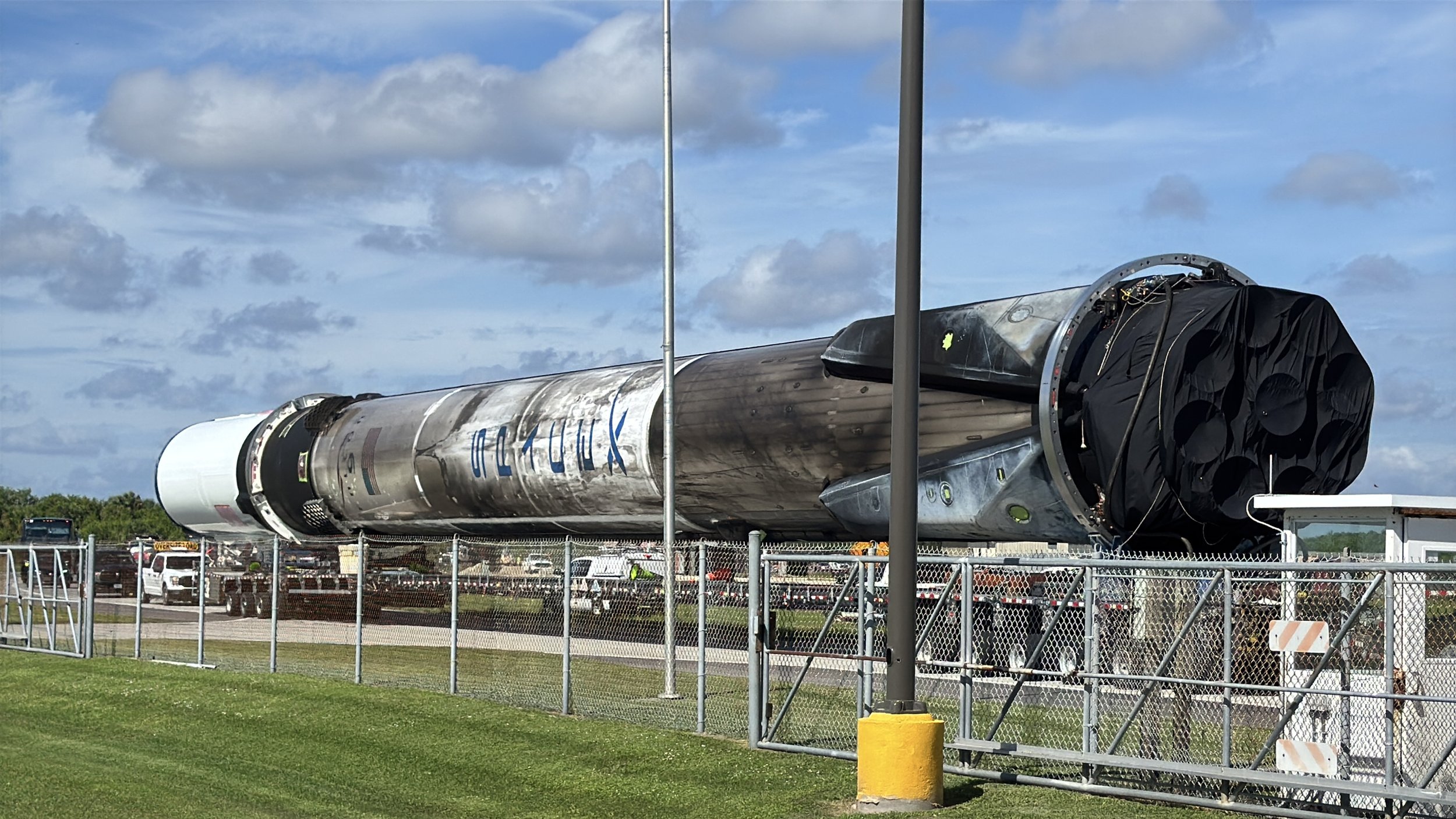 Close view of a flown SpaceX Falcon 9 rocket booster being moved along the roadway near Launch Complex 39.