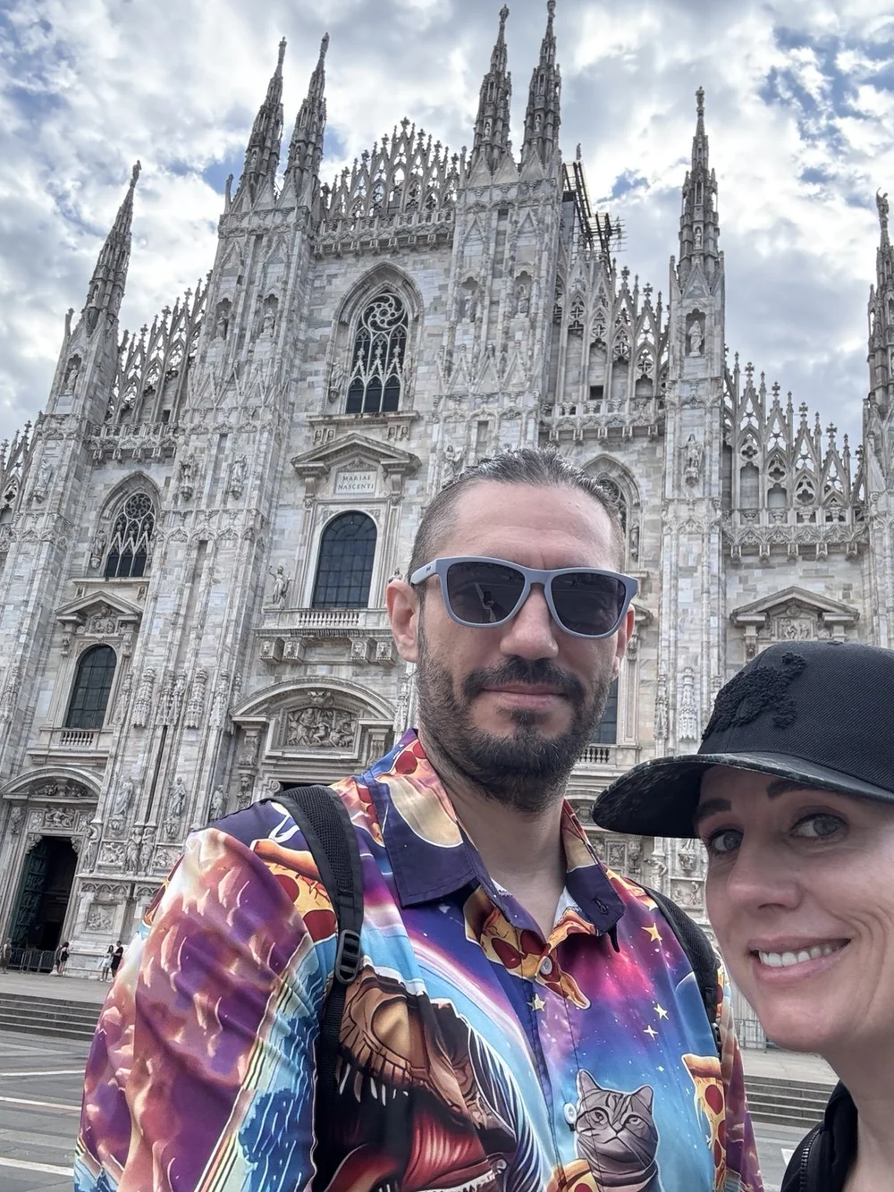 Travelers posing in front of the Gothic facade of Milan Cathedral in Piazza del Duomo