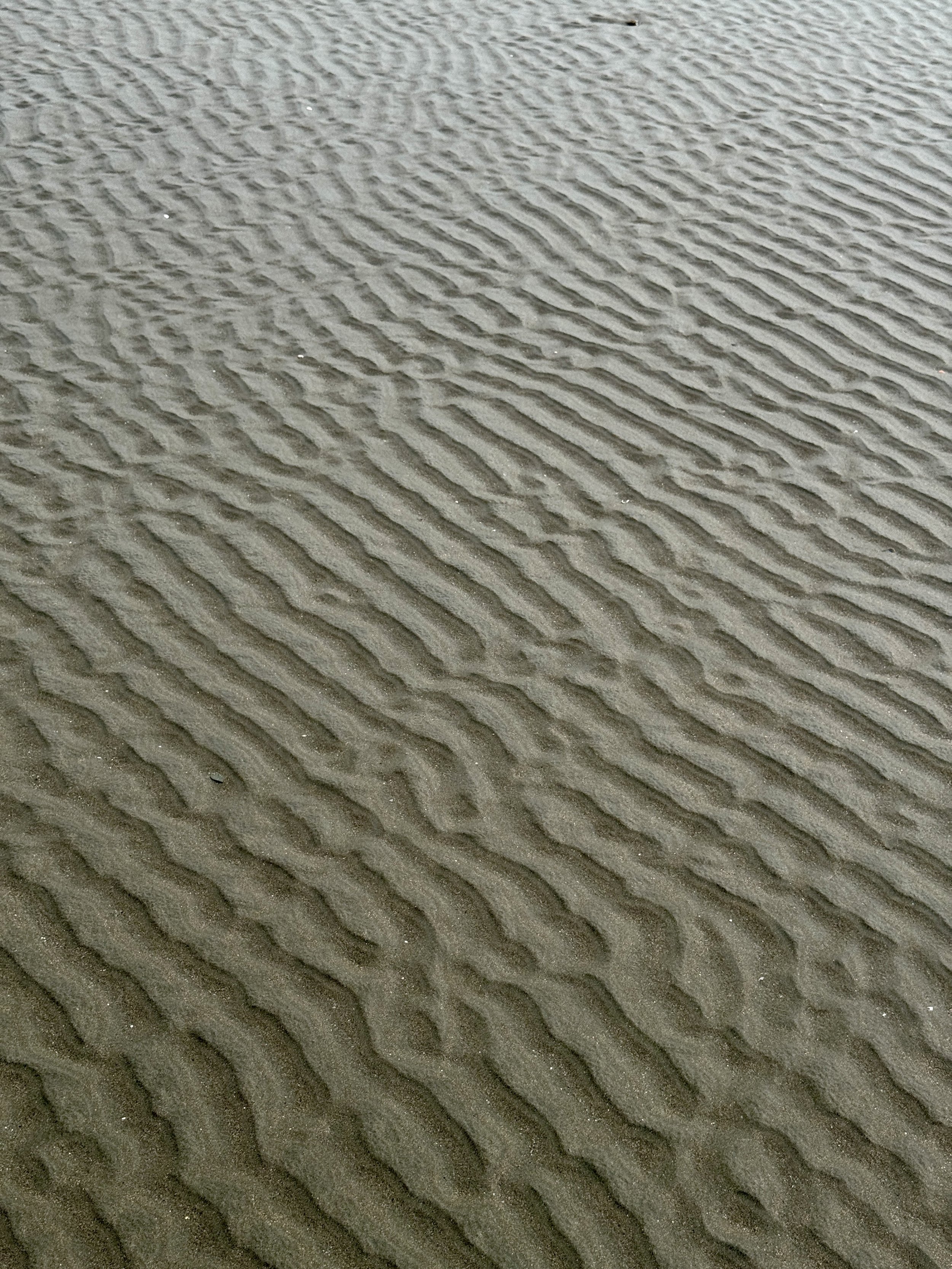 Close-up of rippled sand patterns created by receding tide at Uvita Beach.