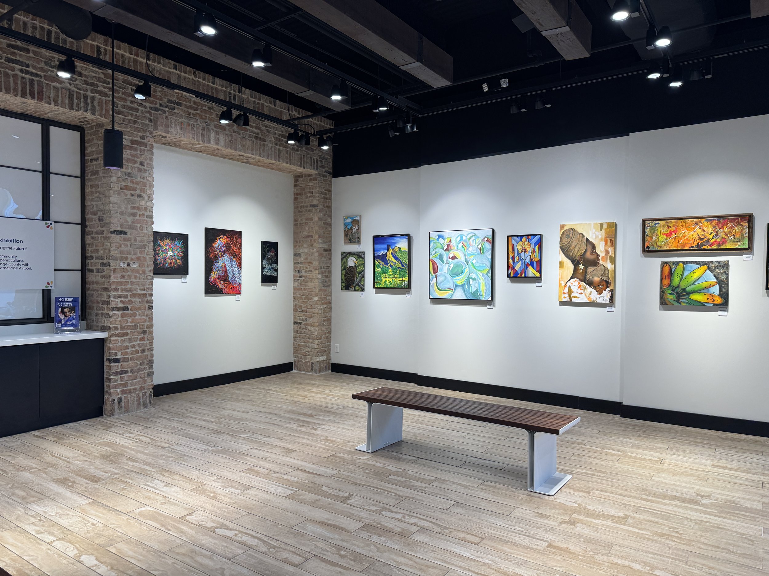 Small airport art gallery with paintings and seating area inside Orlando International Airport.