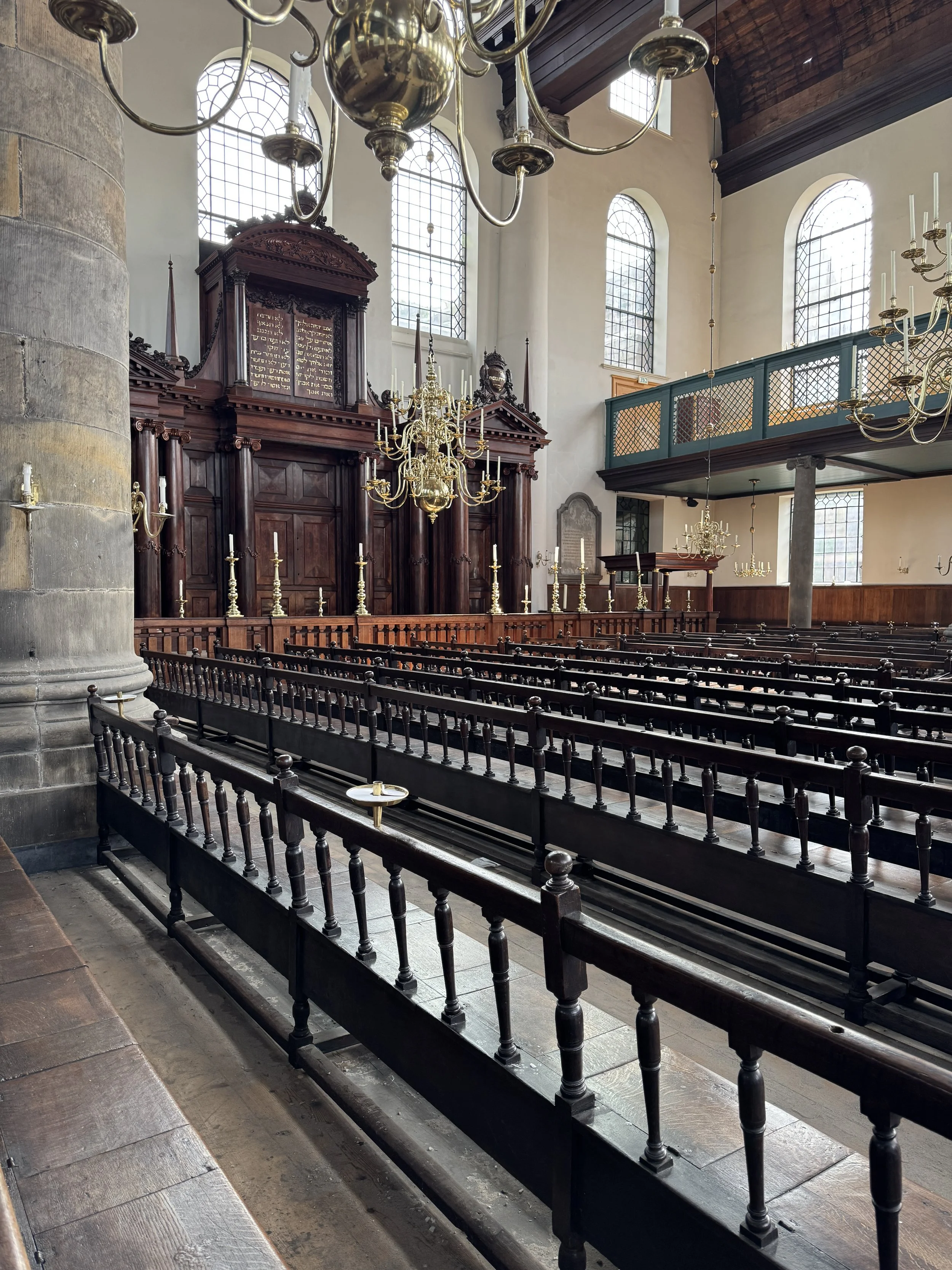 Front view of the Portuguese Synagogue interior with ark, chandeliers, and rows of wooden seating