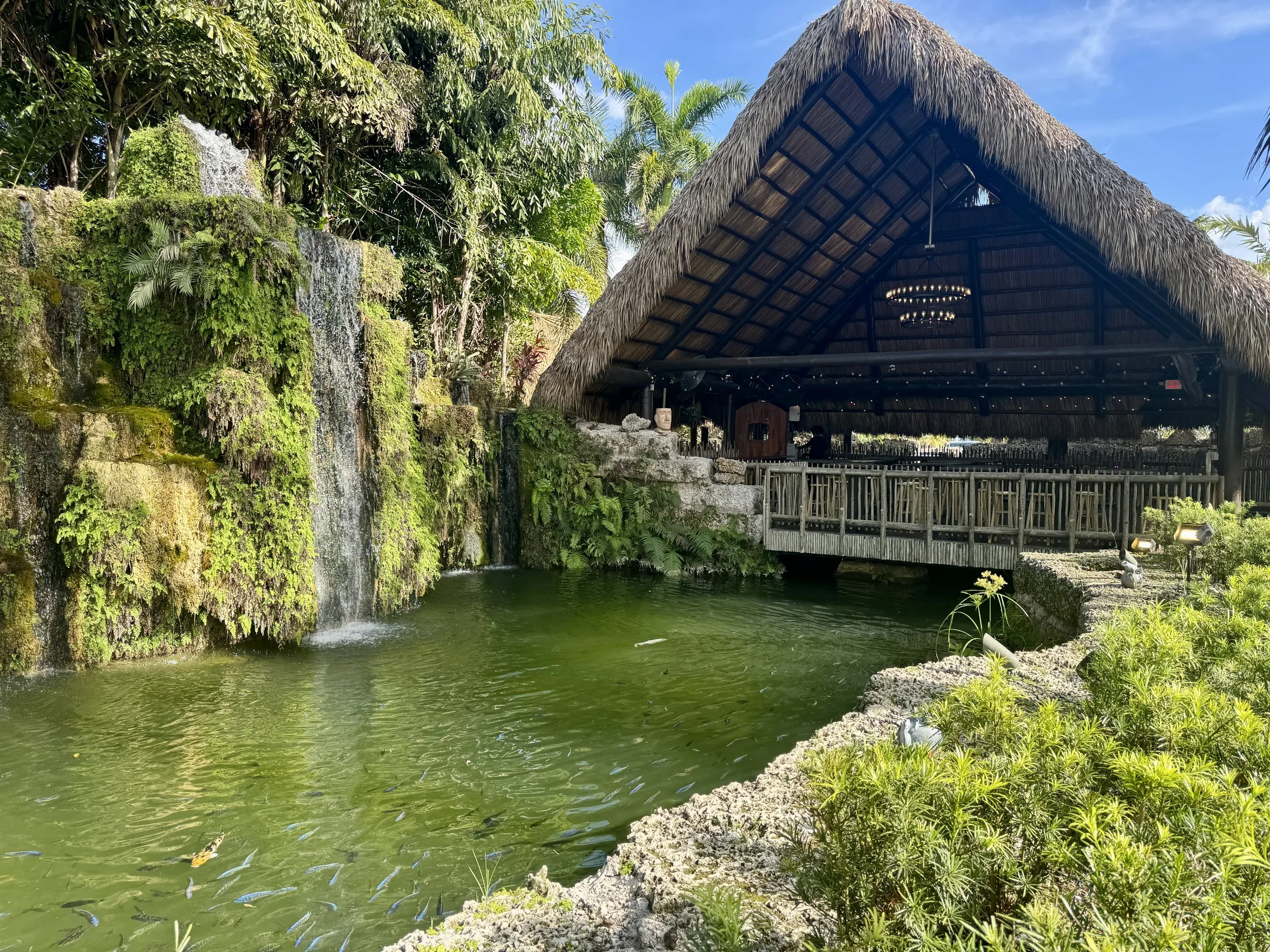 large open air tiki style building at Schnebly Redland's Winery set beside a green lagoon and waterfall