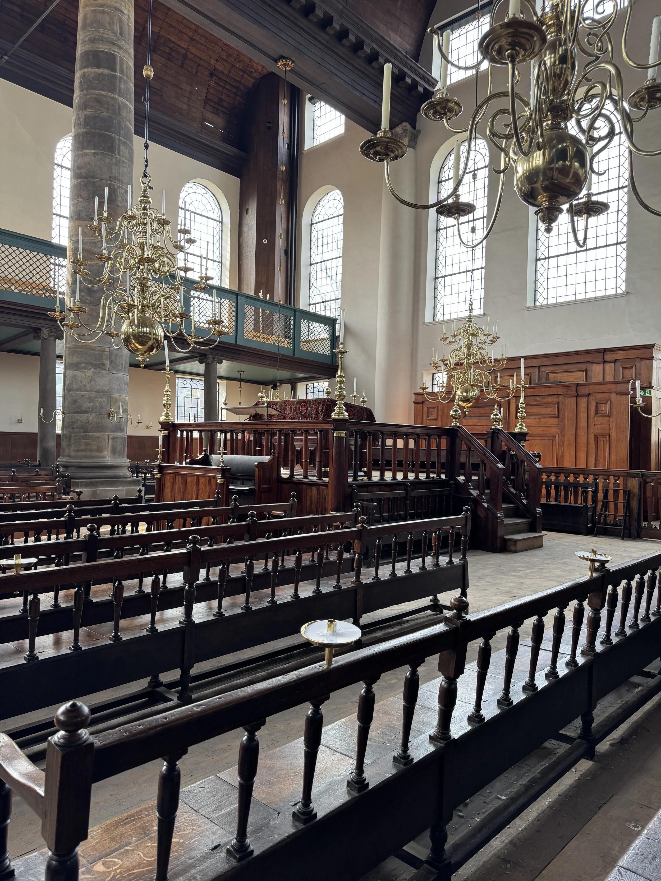 Interior of the Portuguese Synagogue in Amsterdam with wooden benches, chandeliers, and high ceilings