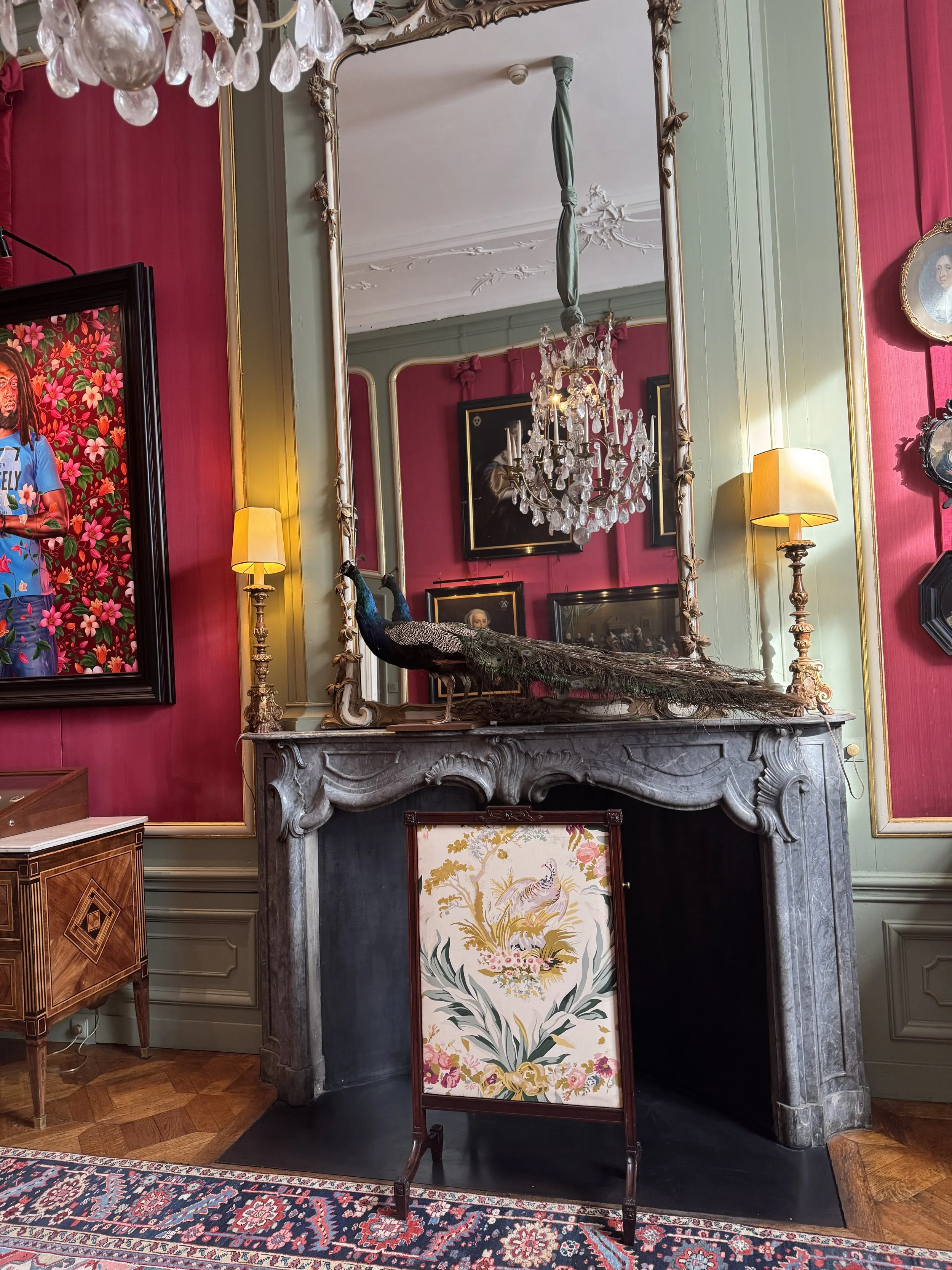 Elegant room with decorative fireplace, mirror, and red walls inside Museum Van Loon Amsterdam
