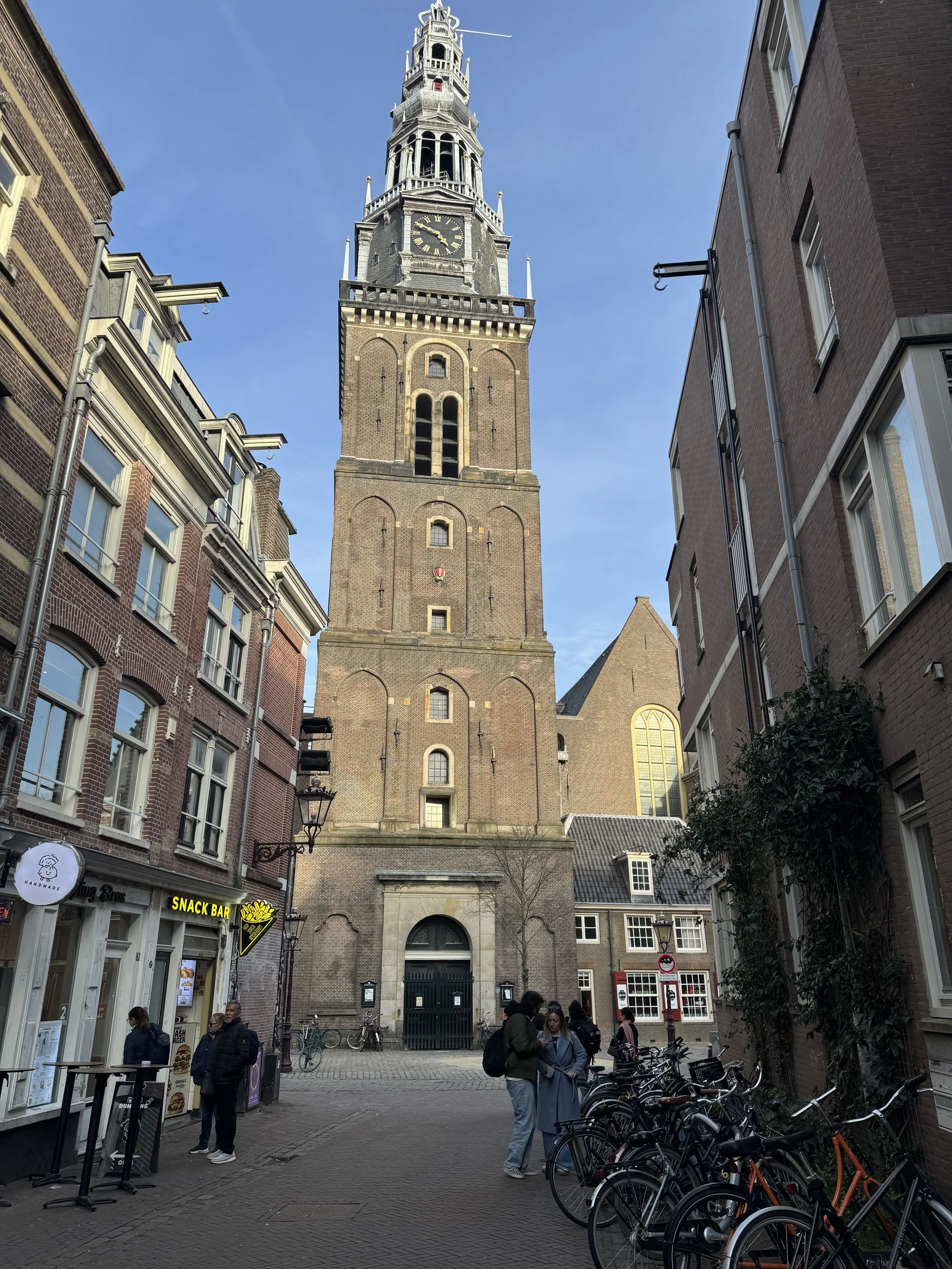Oude Kerk church tower rising above narrow street in Amsterdam city center