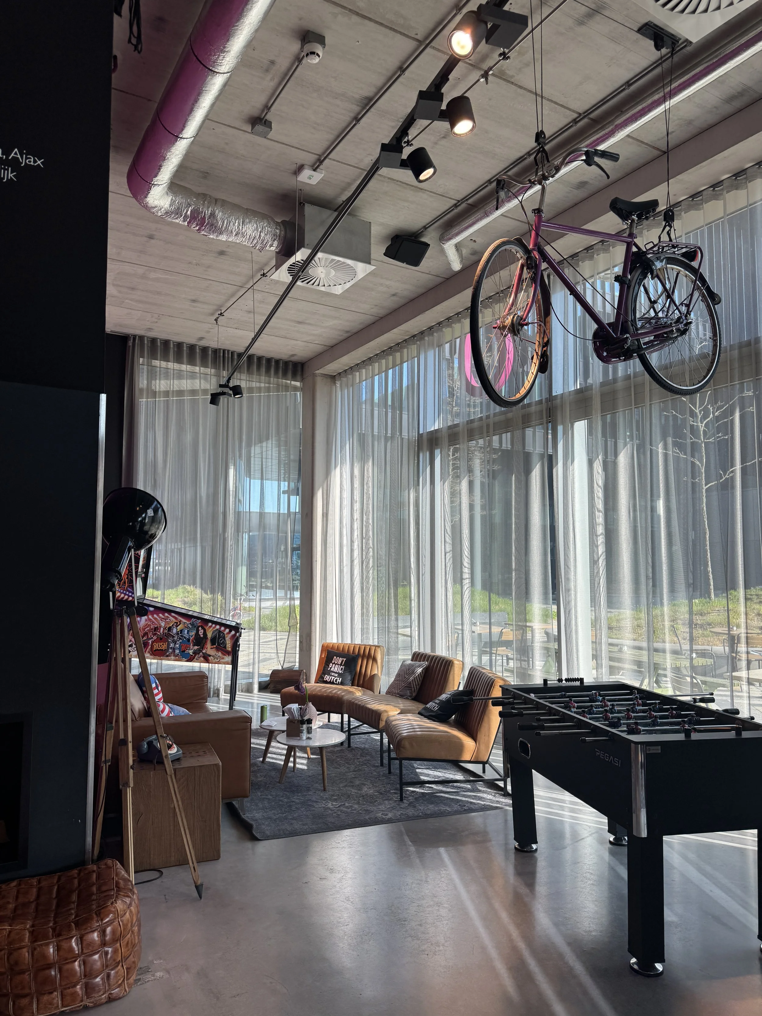 Stylish Moxy Amsterdam hotel lobby with hanging bicycles, large windows, and lounge seating area