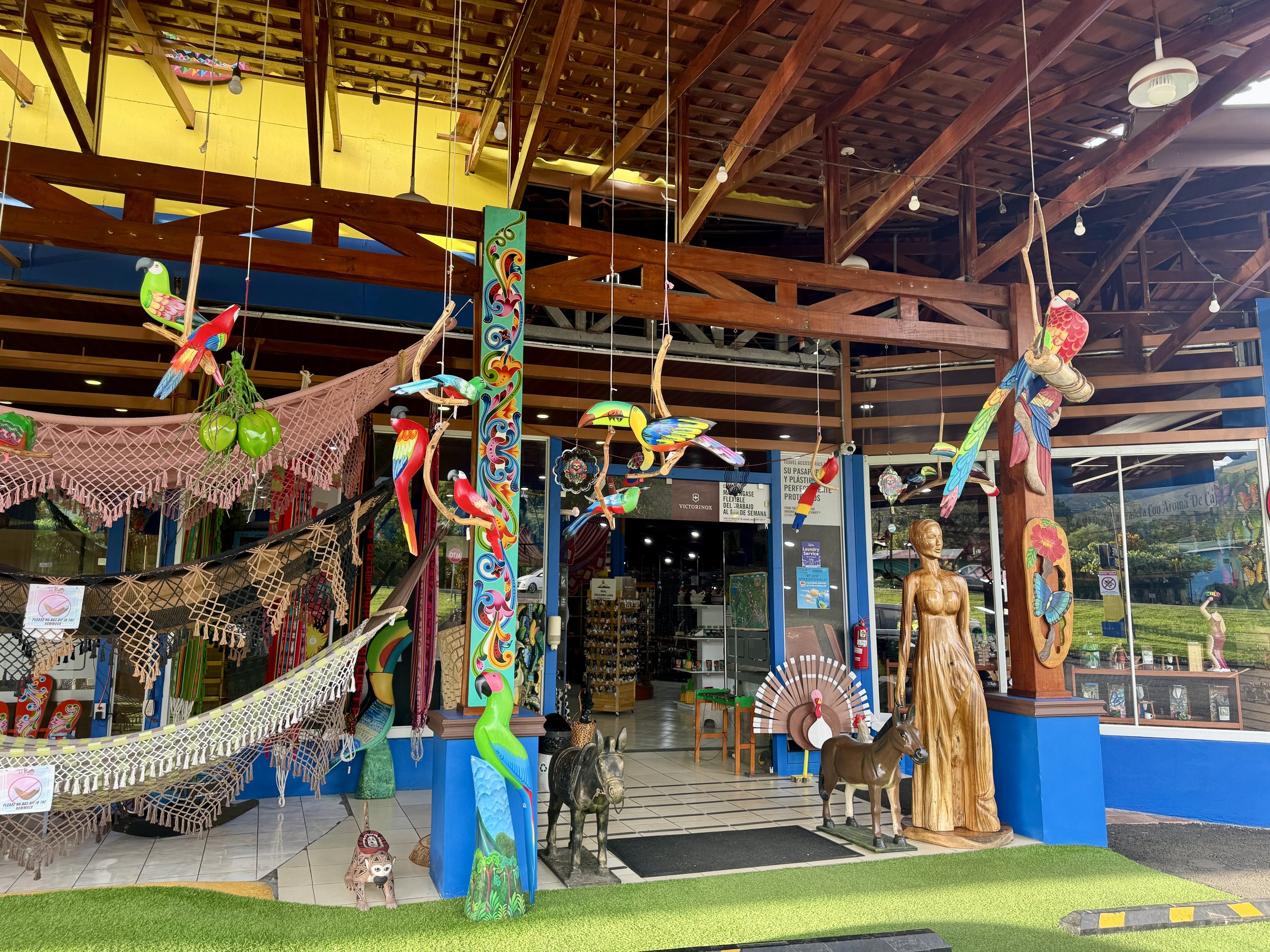 Colorful entrance to La Pradera Souvenirs with hanging decorations and rustic wooden beams.