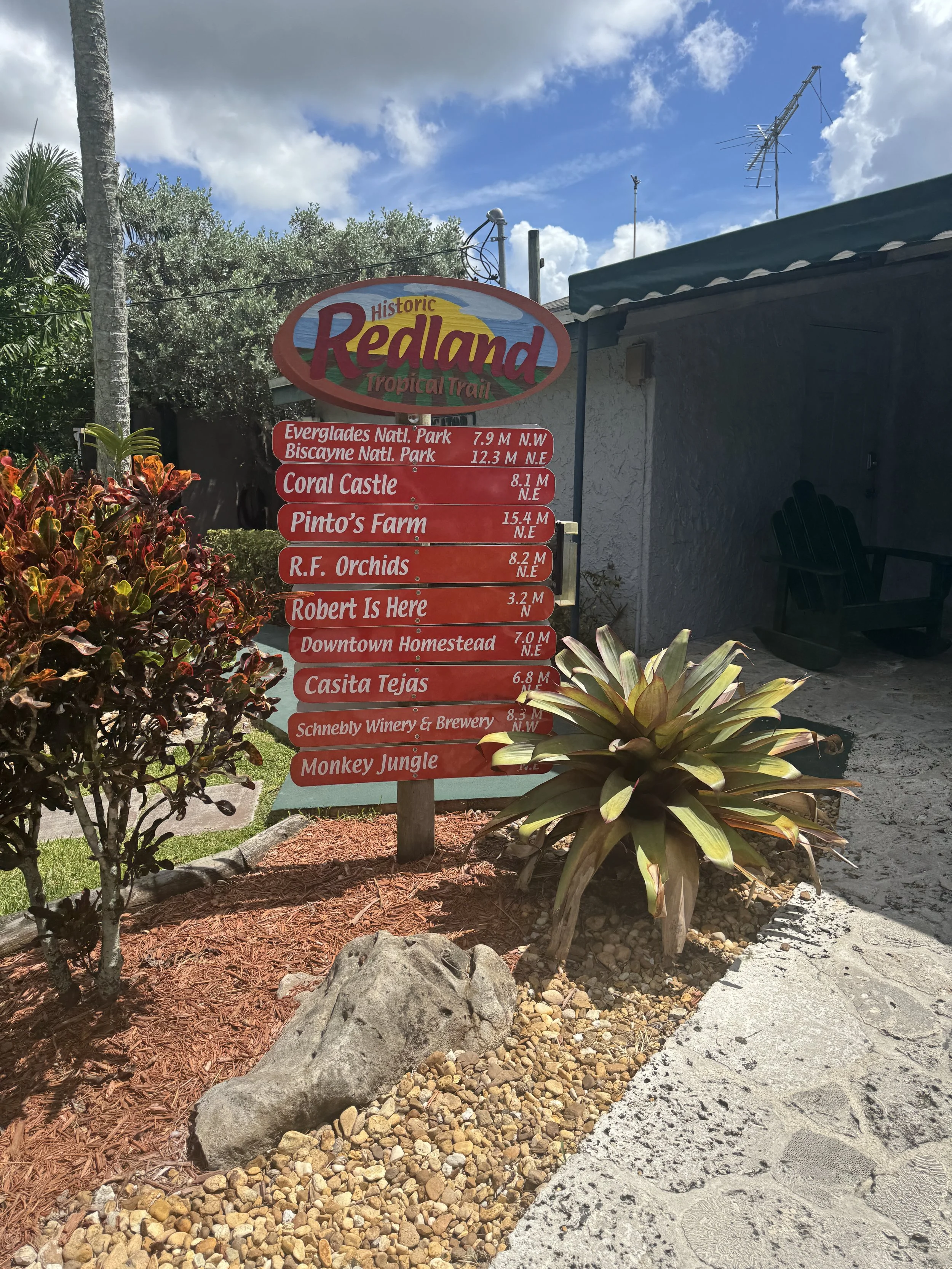 entrance sign at everglades alligator farm surrounded by tropical landscaping