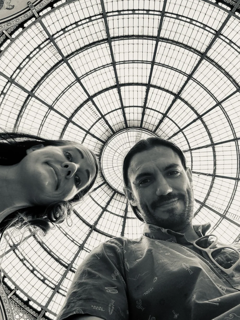 Travel couple beneath the glass dome of Galleria Vittorio Emanuele II in Milan.