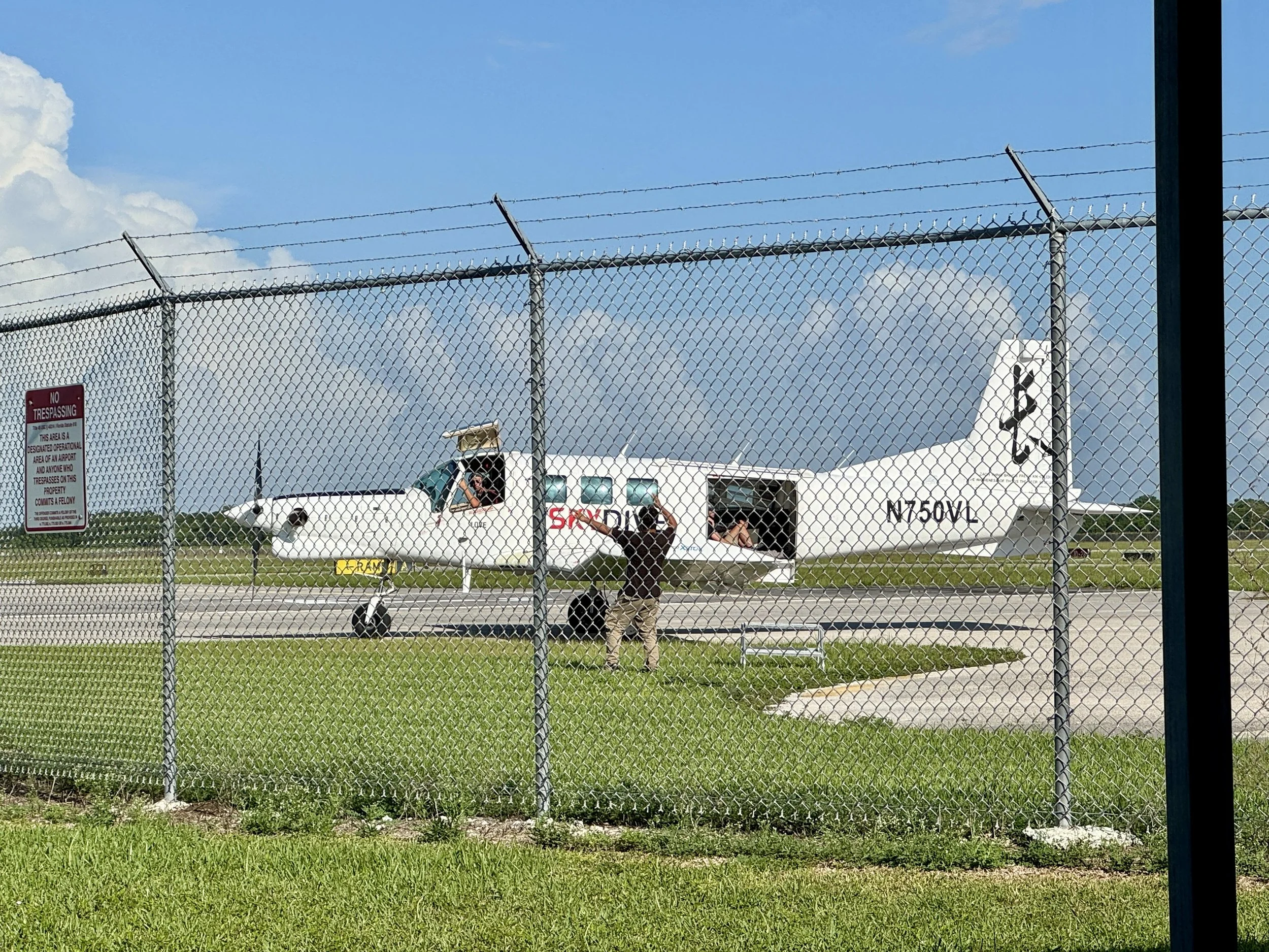 small plane parked near the runway behind chain link fence at Skydive Miami