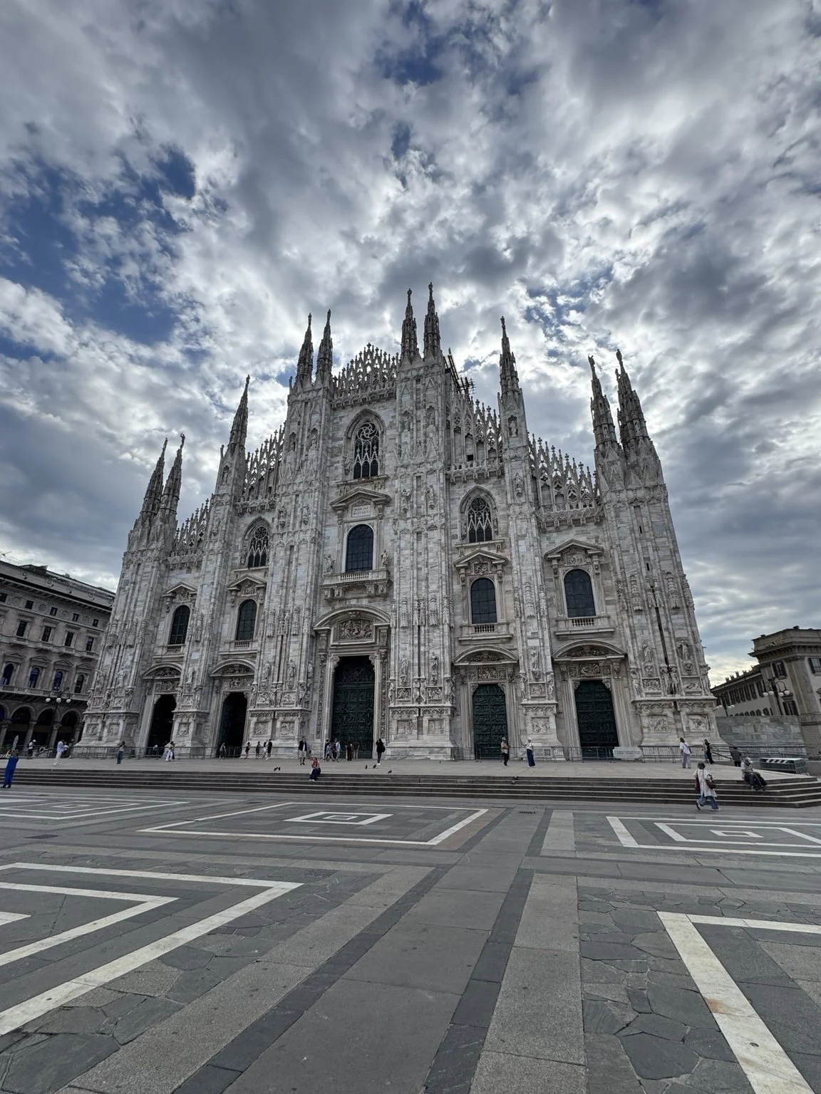 Milan Cathedral exterior beneath dramatic clouds in Piazza del Duomo, Milan, Italy