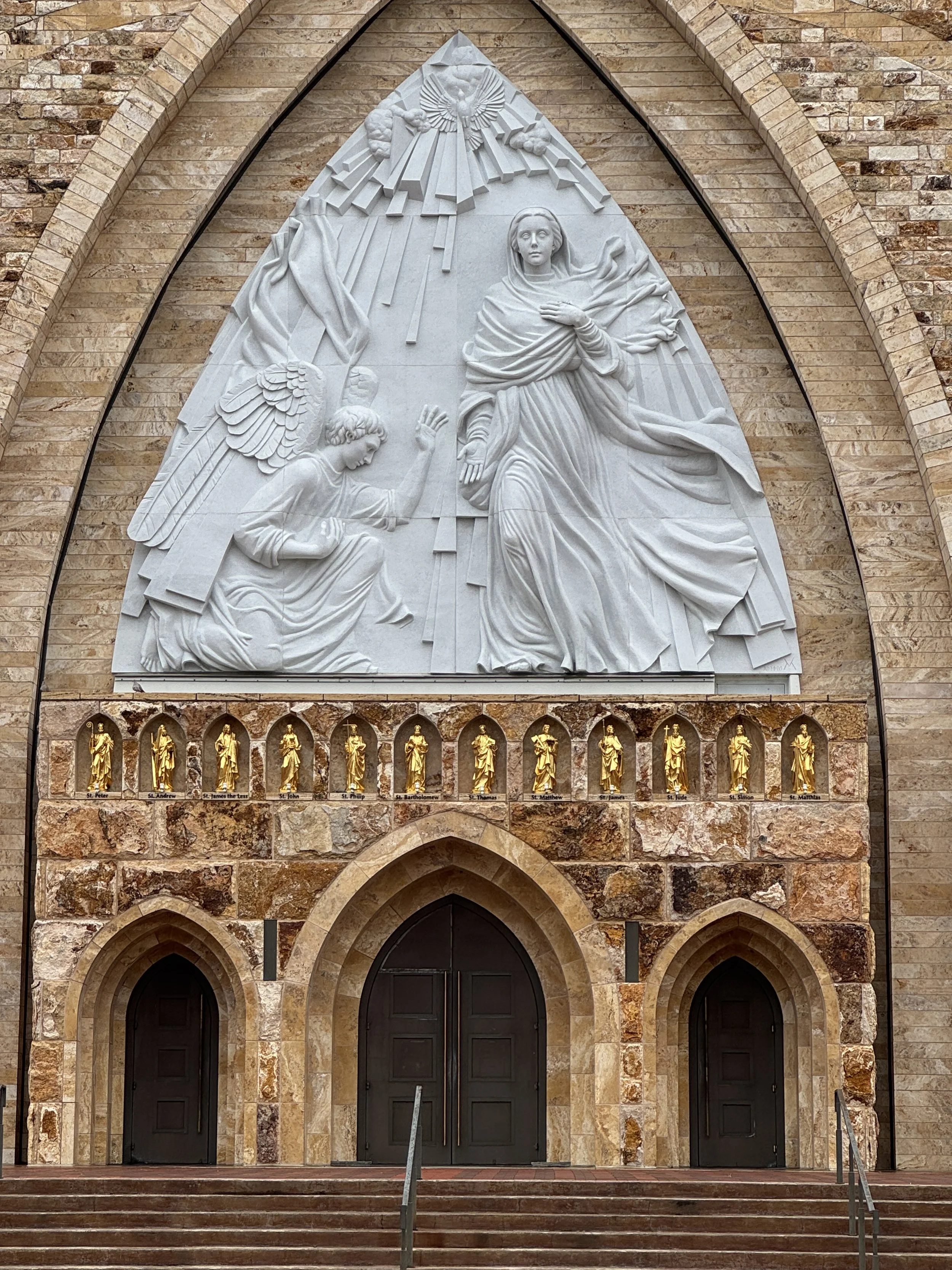 Detailed view of the Annunciation sculpture above the entrance of Ave Maria Catholic Parish Church depicting Archangel Gabriel and the Virgin Mary.