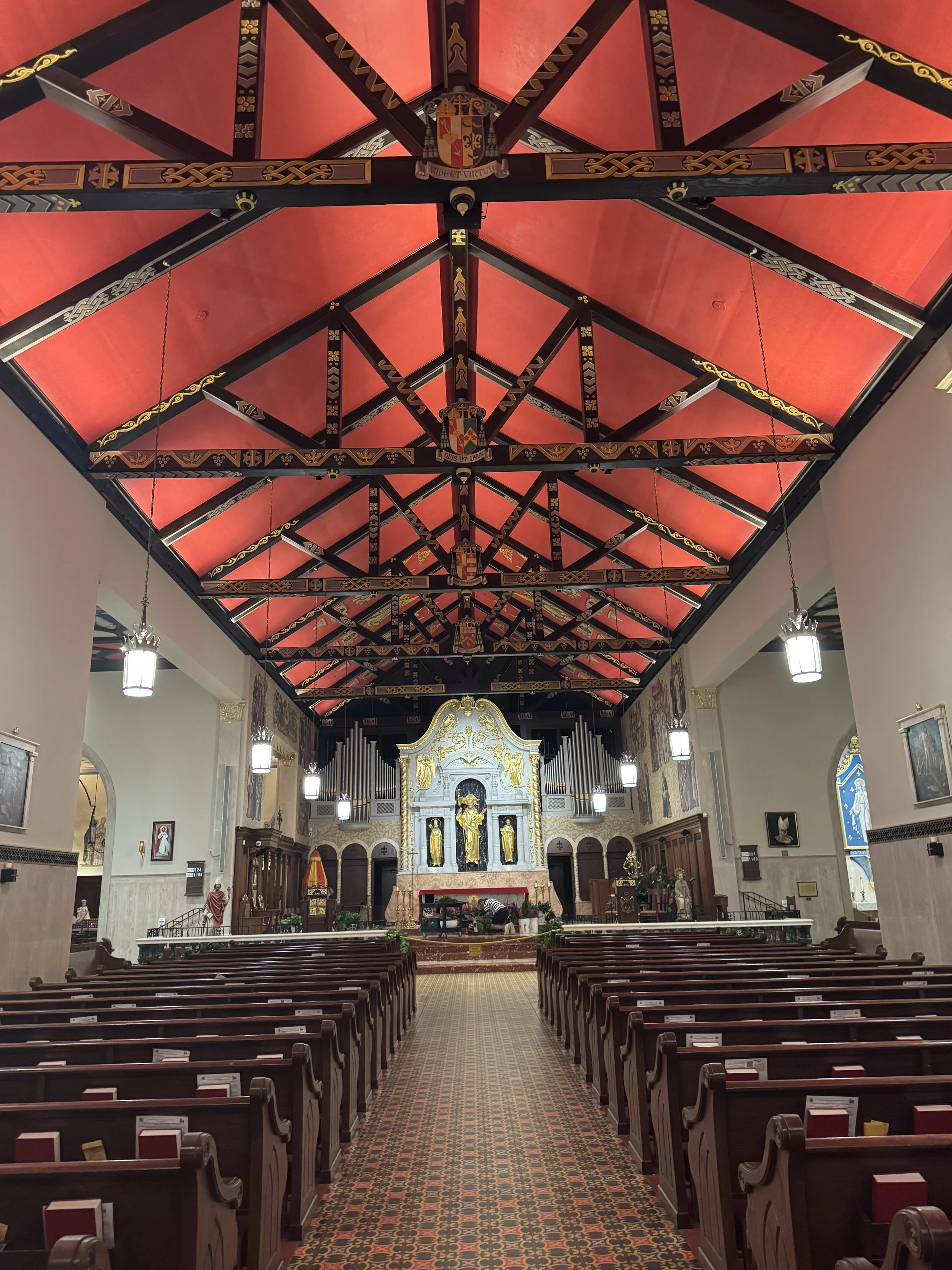 Long nave with wooden pews and red ceiling inside the Cathedral Basilica of St. Augustine Florida.