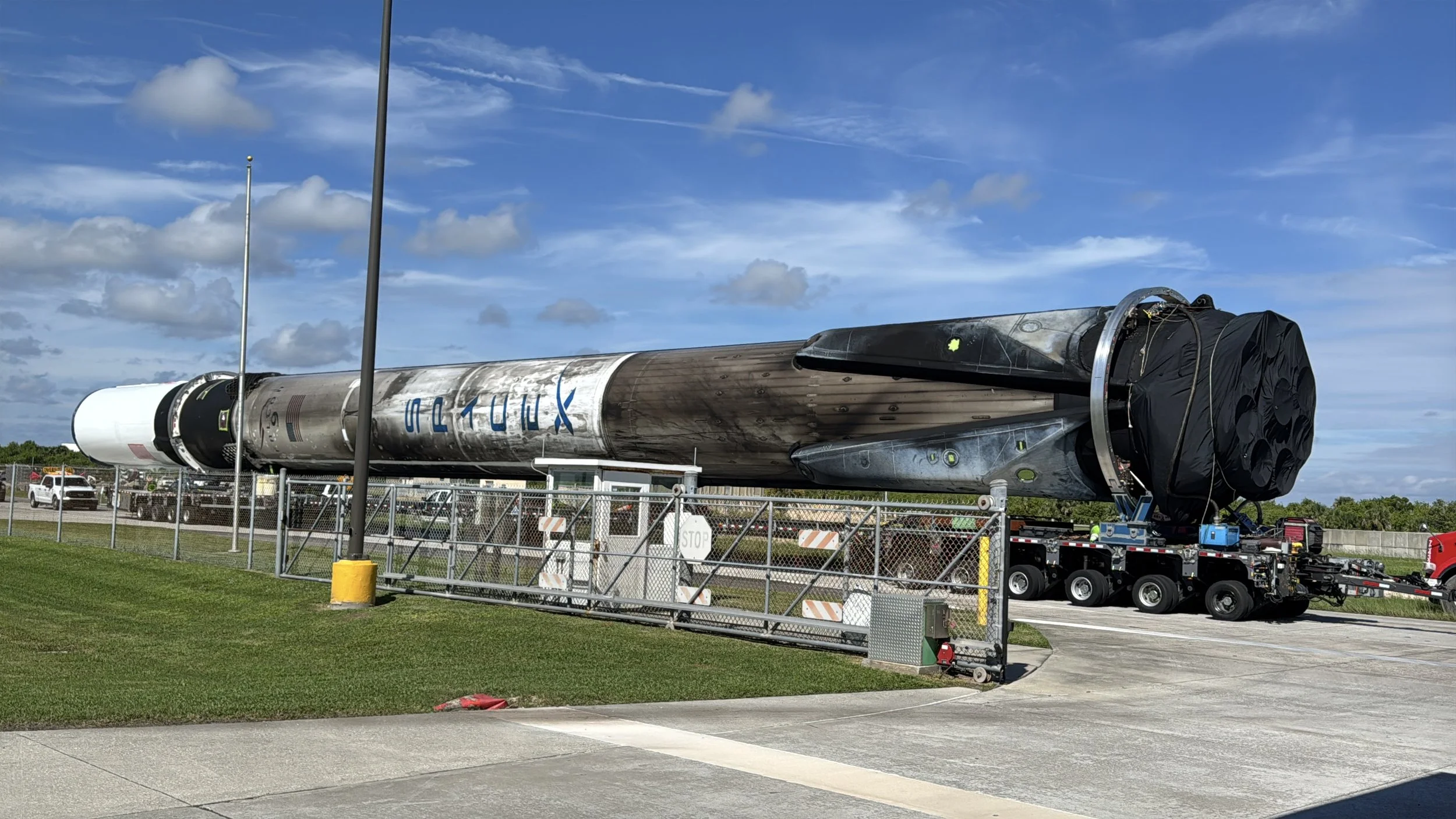 Used SpaceX Falcon 9 rocket booster being transported by truck near Kennedy Space Center.