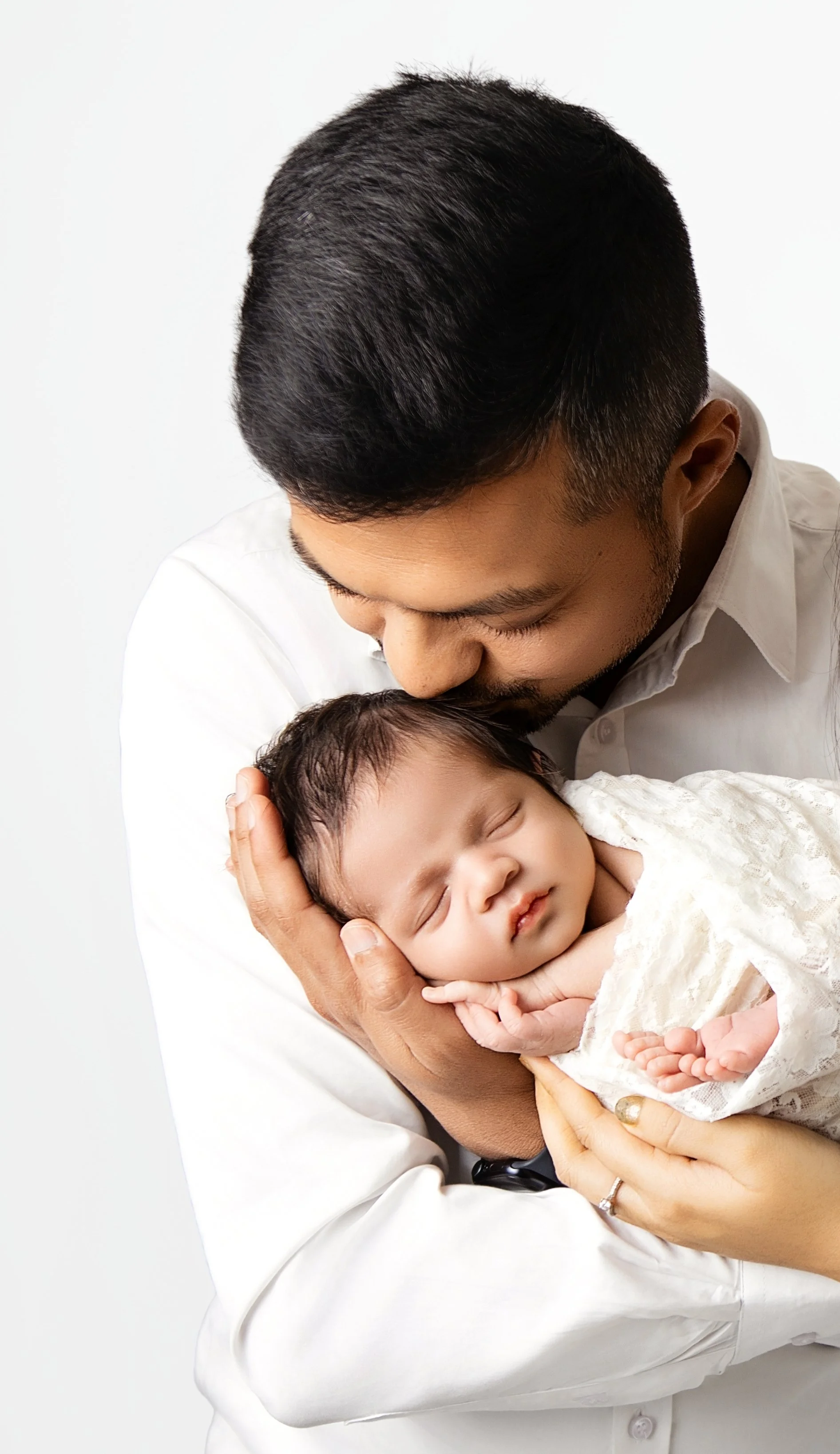 A man holding a sleeping baby close to his face, showing tenderness and affection.