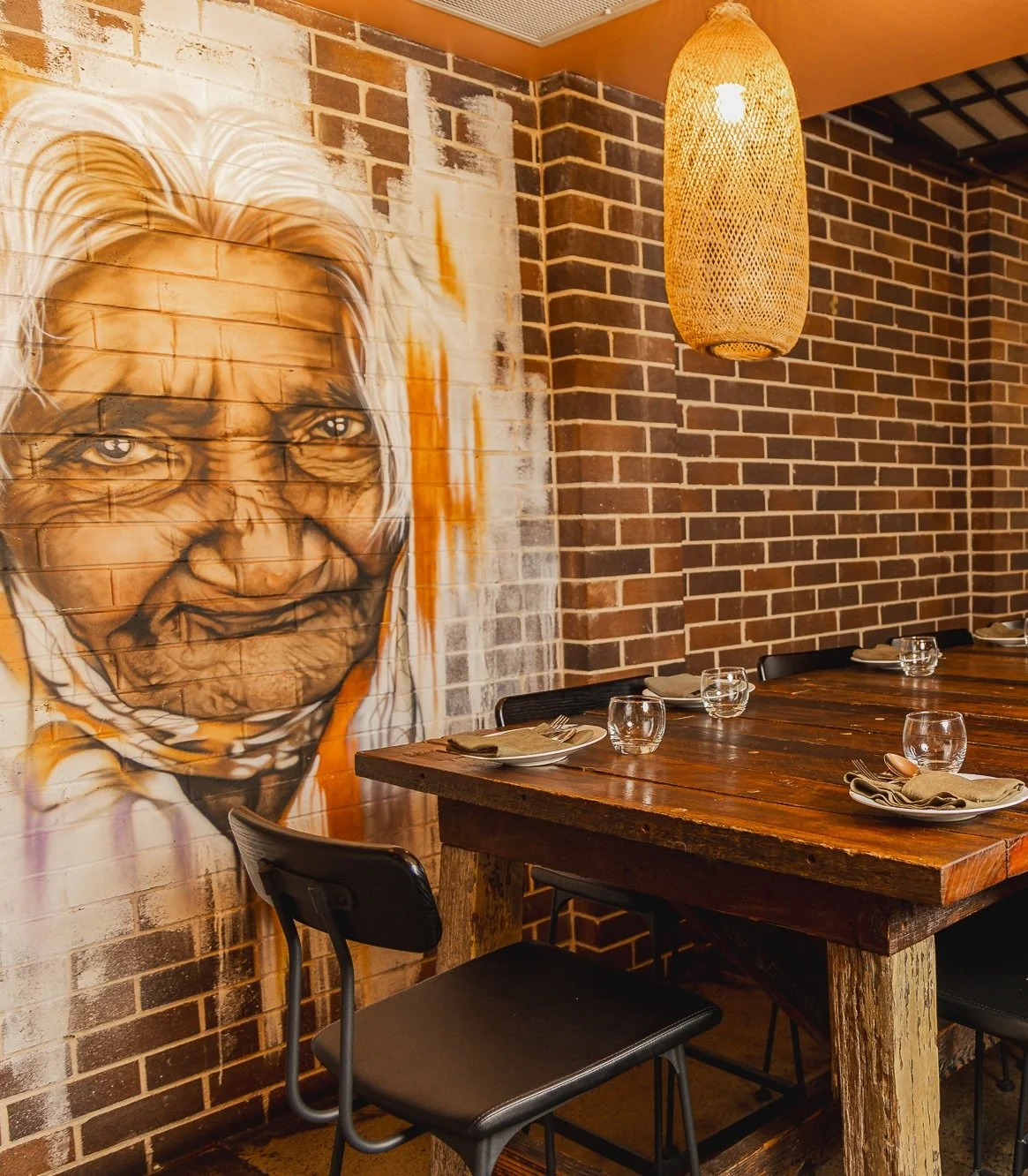 A table setting in front of a mural of a traditional old lady