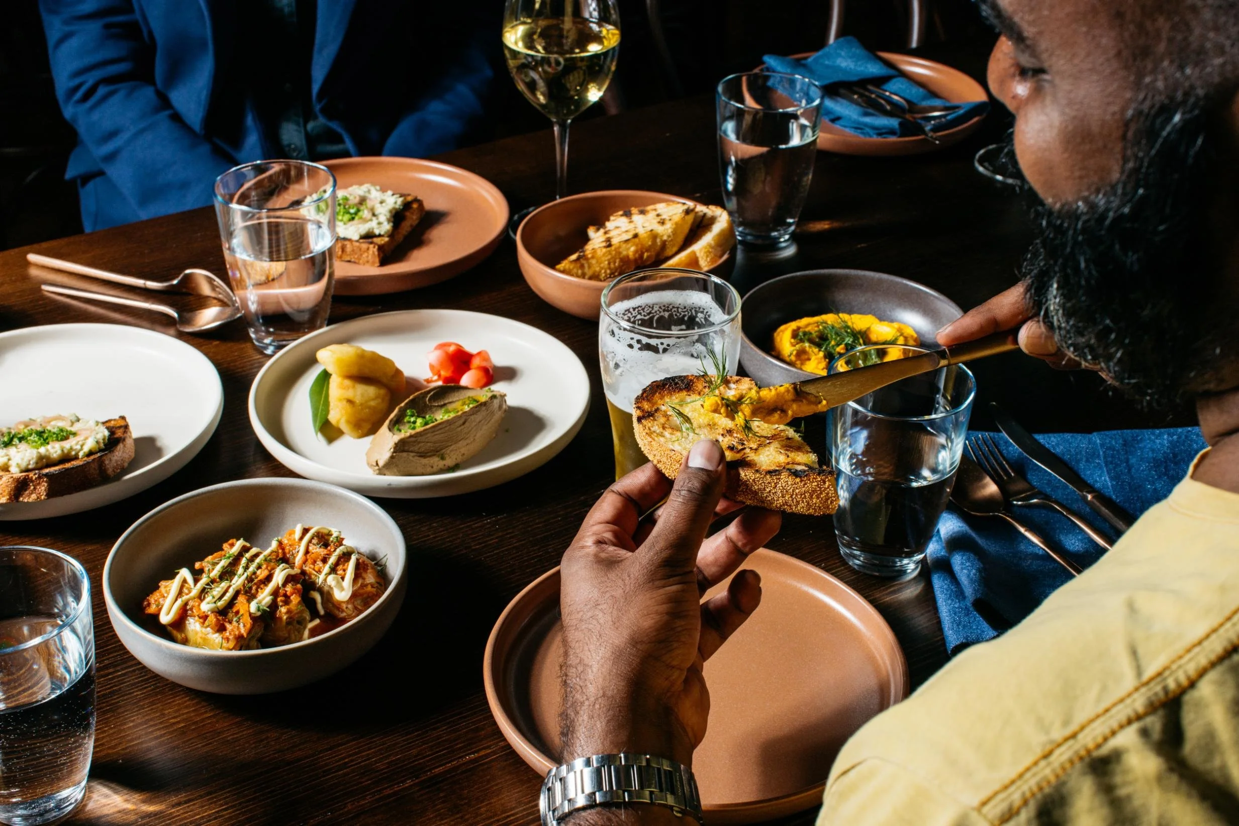 People enjoying a dinner at a restaurant with various plates of food, including bread, pasta, and appetizers, and drinks on the table.